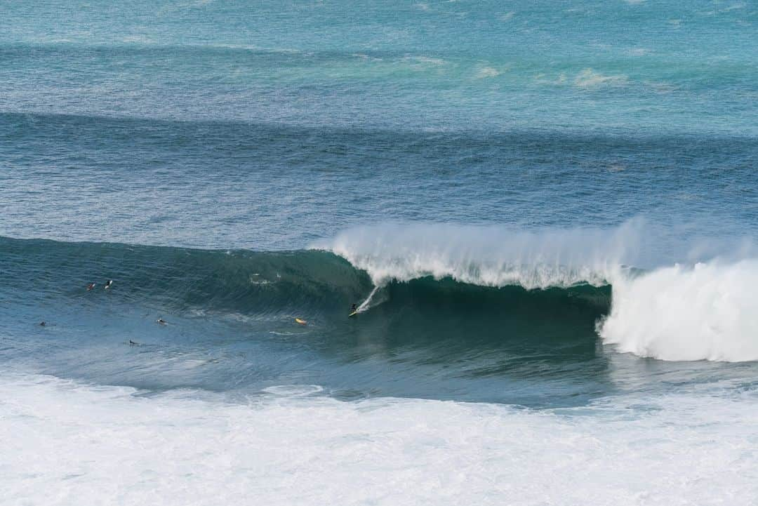 surflineのインスタグラム：「Black Friday at Waimea Bay.   Hours before sun rise, the buoy hit 20.7 feet at 20 seconds. For those who don’t speak NOAA, that’s enormous. We’re talking sand on Kamehameha highway, and legit 25-foot + sets closing out the Bay every half hour.   It was a sleepless night for those closest to shore. The ground was shaking with every set. Waves washed into homes and took what they wanted from them.   Even the deepest of sleepers would toss and turn as the roar of the ocean rumbled all the way up Pūpūkea.  One surfer would paddle out to Waimea Bay, alone and in the dark.   At dawn, big wave surfers would arrive to watch Tripp Turner, a Pastor , whose congregation meets every Sunday in Waimea Valley, dodge closeout sets and ride the first waves of the day. Many would soon join him.  Up at the Heiau,  @jackboberphoto, sat with his long lens and snapped this shot of @ealadolla riding a mountain. From this vantage point, you can almost understand the enormity of what surfing Waimea means to the brave men and women who answer its call.   Click the link in bio for the #swellstory and stay tuned to the forecast for the next one. 🤙🏼」