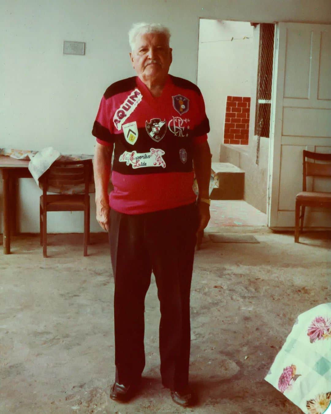 ジーコのインスタグラム：「Imagem rara do Seu Antunes, encontrada nos álbuns de família do @eacoimbra. (10.06.84)  Detalhes: Era uma camisa personalizada para o seu aniversário de 83 anos, com o número 83 estampado atrás.  Explicando a salada de escudos:  - Zico ainda jogava na Udinese; - Zeca (Antunes) treinava o Olaria; - Edu treinava o Vasco; - Aquim, antiga loja de tecidos do Centro do Rio do Sr. Elias Aquim, amigo da família; - A Nacif Esporte LTDA é uma loja de material esportivo que fica na Rua Buenos Aires, Centro, RJ. Na época, Nacib Nacif, flamenguista nato, era dono da loja e amigo do Galinho; - CBF porque o Zicão ainda estava por lá.  E claro, a camisa base escolhida foi do @Flamengo porque o velho Antunes era MENGÃO PRA CAR@LEO.  📷📝 @eacoimbra (Twitter)」