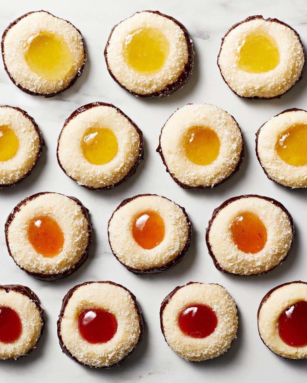 マーサ・スチュワートのインスタグラム：「Looking for recipes for your upcoming cookie swap? These sunny thumbprint cookies are a riff on classic Australian Lamingtons—small cubes of sponge cake layered with jam, dipped in chocolate, and coated with coconut flakes. The soft, chewy cookies are made from an easy dough that comes together with just a bowl and whisk. After baking, simply dollop your favorite preserves in their centers and round up your closest mates for tea. Get the recipe at the link in our bio. 📷: @chrisrsimpson recipe: @brooklyncooks」