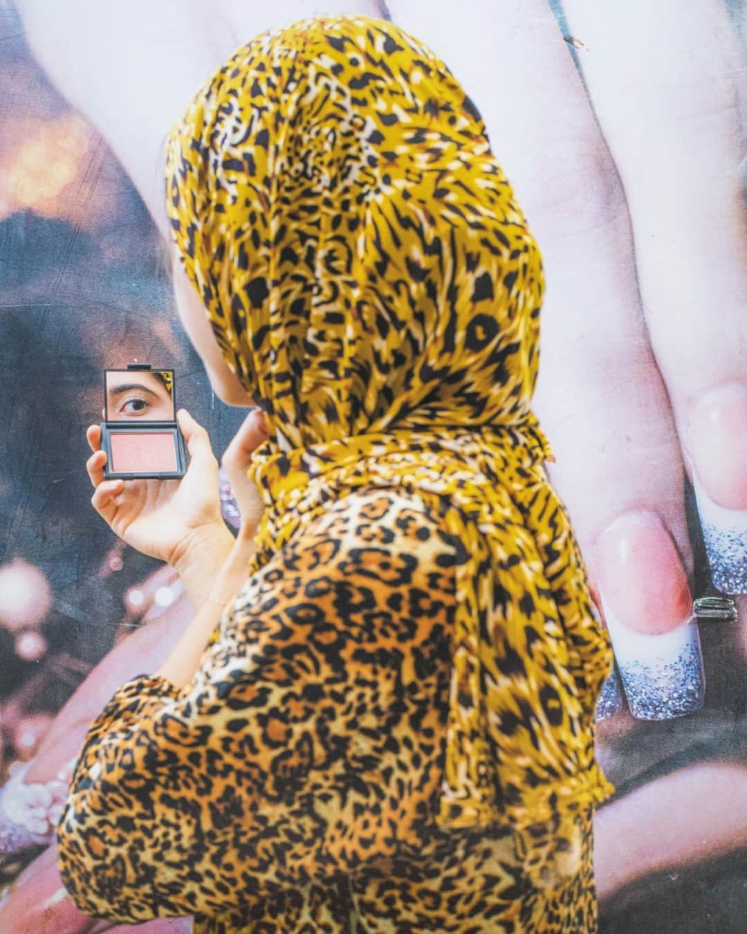 グッゲンハイム美術館のインスタグラム：「Farah Al Qasimi approaches visibility and concealment ambiguously, paying keen attention to pattern and self-adornment.  Al Qasimi's photographic practice questions prevailing narratives around Arab culture and captures her subjects through sitters who are not wholly identifiable.  In this portrait, a figure in a bold-printed hijab turns away from the camera toward a mirrored compact, which reflects back to the viewer a heavily made-up eye—a gaze that is at both evasive and direct.  This work is on view in #GoingDarkGuggenheim.  ... 📷: Farah Al Qasimi (@frequentlyaskedquestion), "Woman in Leopard Print," 2019. Courtesy of the Artist and François Ghebaly Gallery. © Farah Al Qasimi #FarahAlQasimi」