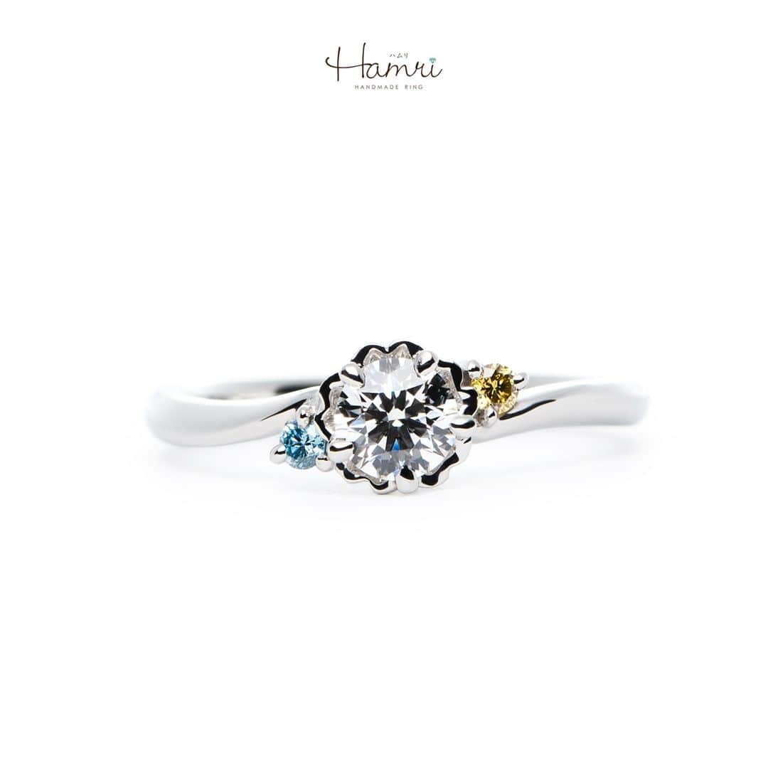 結婚指輪・婚約指輪『Hamri(ハムリ)』さんのインスタグラム写真 - (結婚指輪・婚約指輪『Hamri(ハムリ)』Instagram)「【桜モチーフの婚約指輪をご紹介です】  まるで桜の花が指先で優雅に舞っているような婚約指輪です。  指輪のデザインには、イエローダイヤモンドとアイスブルーダイヤモンドが使われ、春の温かな光と清涼な空気を映し出しています。  イエローダイヤモンドは、まるで春の太陽のような明るい輝きを放ち、その暖かさが愛の温もりを象徴しています。  一方、アイスブルーダイヤモンドは、爽やかな春の空を思わせる爽快な輝きで、新たな始まりと希望を表現しています。  桜の花びらを模した繊細なデザインは、ロマンティックで洗練された雰囲気を醸し出し、指輪を着けるたびに、お二人の特別な瞬間を思い出させます。  この婚約指輪は、愛の約束を華やかに、そして心温まる形で表現してくれるでしょう。  まさに、春の訪れを告げるような、幸せ溢れる指輪です。  ご婚約おめでとうございます！  💓ふたりらしい指輪と想い出を💓 @hamri_omotesando ==========================  ♦︎♢作成中の写真や動画を撮影、全データプレゼント♢♦︎  DMやLINEでのご相談お待ちしております♥ ⇒@hamri_omotesando  ❁・❁・❁・❁・❁・❁・❁・❁・❁・❁・❁  ＊セットリング5%OFF＊  @hamri_omotesando  Hamri「ハムリ」  〒150-0001 東京都渋谷区神宮前5-11-11 2F  tel 0120-121-175 hp https://hamri.jp/  open 11:00〜19:00 close 火/水　祝日営業  ❁・❁・❁・❁・❁・❁・❁・❁・❁・❁・❁  #手作り結婚指輪 #手作り婚約指輪 #結婚指輪#マリッジリング #エンゲージリング #プレ花嫁 #Hamri #Hamri表参道 #オーダーメイドリング #鋳造 #ブライダルリング #ペアリング #鎚目リング #プラチナリング #ピンクゴールド #シャンパンゴールド #ゴールドリング #コンビネーションリング #2023wedding #2023春婚 #2023夏婚 #プレ花嫁準備 #プレ花嫁と繋がりたい #結婚指輪探し #結婚指輪選び #結婚準備  《Hamri検索タグ》  #hamriデザイン #hamri指輪作り #hamri花嫁」11月30日 17時45分 - hamri_omotesando