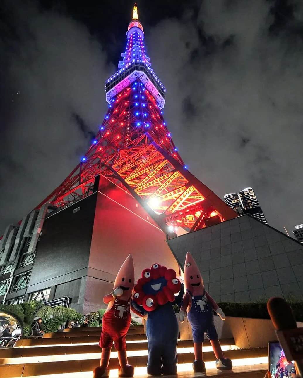 東京タワーのインスタグラム：「. 昨日（11/30）は、 大阪・関西万博開幕500日前でしたね。  東京タワーは、万博カラーであり、 公式キャラクター『ミャクミャク』のカラーでもある 赤と青の特別カラーでライトアップしました✨   『ミャクミャク』も東京タワーに駆けつけてくれて ノッポン兄弟（ノッポン兄弟も赤と青！）と一緒に ライトアップを楽しみました♪   本日はYour Tokyo Tower🗼から @orangebarm さんのお写真をご紹介！   東京タワースペシャルライトアップと共に 貴重なスリーショット！！！   素敵なお写真をありがとうございました😊  ––––––––––––––––––––––––––––  【ミャクミャクの愛称コンセプトのご紹介！】   今まで「脈々」と受け継がれてきた 私たち人間のDNA、知恵と技術、歴史や文化。  変幻自在なキャラクターは 更にあらゆる可能性をその身に宿して、 私たち人間の素晴らしさを これからも「脈々」と未来に 受け継いでいってくれるはず。  そんな希望を込めて 「脈々＝ミャクミャク」と名付けられました。  またミャク＝脈であり、生命そのもの。  ミャクミャクという2音が続く様は、 命が続いている音にも聞こえます。  ––––––––––––––––––––––––––––  #東京タワー #東京タワー🗼  #tokyotower #tokyotower🗼  #万博 #ミャクミャク」