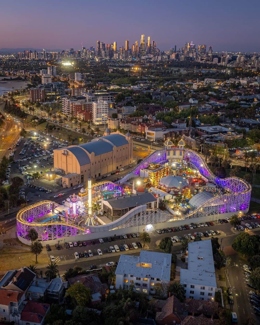 Australiaのインスタグラム：「Just #Melbourne's icons posing for a quick pic 😉📸 Kudos to our mate @a.j.wilko for sharing this stunning perspective of Narrm (@visitmelbourne), shot from above #StKilda's iconic @palaistheatre and @lunaparkmelb. You'll find this seaside suburb just 20 minutes from the city centre. Once here, soak up the carnival atmosphere and jump aboard #LunaPark's Great Scenic Railway for jaw-dropping views of the city and #PortPhillipBay.   #SeeAustralia #ComeAndSayGday #VisitVictoria #VisitMelbourne  ID: A nighttime aerial view captured from above showcases a brightly illuminated theme park and its surrounding suburb. The park's lights create a vibrant glow, while in the distance, a city skyline can be seen.」