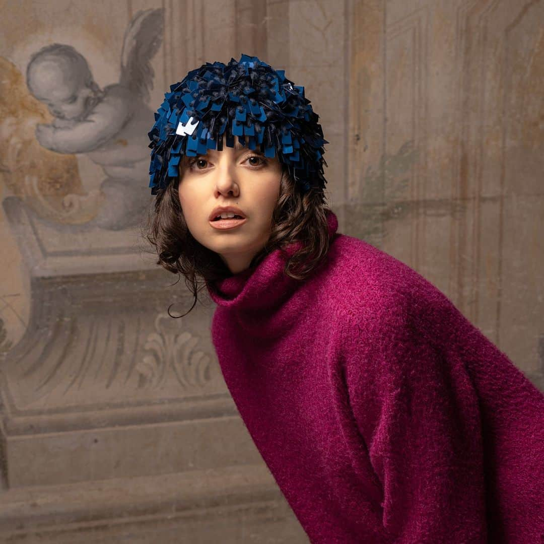 グレヴィのインスタグラム：「@anitabertuccelli is wearing one of our iconic winter styles: a sparkling blue hat. A hat entirely handmade by crocheting alpaca wool threads and rectangular sequins. This marvel of craftsmanship merges with one of the frescoes of Palazzo Ximènes Panciatichi, a prestigious Florentine residence, located within the walls of the Tuscan capital, immersed in a fascinating green garden, which is the backdrop to our shots.  ----------------------- Photographer: @_marcopasquini_ Makeup: @virginia.simonatti.mua Special thanks: @abecherucci for the location -----------------------  #Grevi #InspiringTraditions #MadeInItaly #since1875  #sparklingbluehat  #craftsmanship  #winterstyle #alpacawool  #sequins #sequinhat  #crocheting  #handmade」