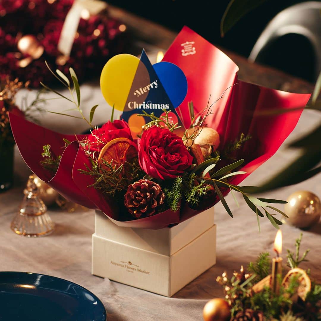 青山フラワーマーケットさんのインスタグラム写真 - (青山フラワーマーケットInstagram)「ブリリアンスBOX  テーブルやリビングに、ひとつ置くだけで クリスマスの主役になる華やかさ。  ホリデームードあふれるアイテムをボックスに詰め込んだ この季節だけのアレンジメントです。  赤バラに、クリスマスの香りが漂うグリーン、 松笠やシナモンピックなどをあしらいました。  お気に入りの場所を華やかにしてくれる ブリリアンスBOXを飾ってホリデーシーズンを お楽しみください。  ＊ ＊ 12月6日(水)20時15分〜配信の インスタライブでも紹介します。  12月10日(日)までフォトコンテストも開催中。 季節の花やグリーンを楽しんでいる写真に #青山フラワークリスマス  のハッシュタグをつけて投稿してください。  素敵な投稿をしてくださった5名様に クリスマスブーケをお届けします。  #フラワーアレンジメント #贈り物 #花束 #バラ #薔薇 #クリスマス #青山フラワークリスマス #アドベント #ブリリアンスボックス #アレンジメント #花のある暮らし #花のある日常 #花を楽しむ #青山フラワーマーケット #aoyamaflowermarket  #Christmas #MerryChristmas  ※ブリリアンスBOXの発売時期は、店舗により異なります。予め、ご了承ください。」12月5日 17時30分 - aoyamaflowermarket