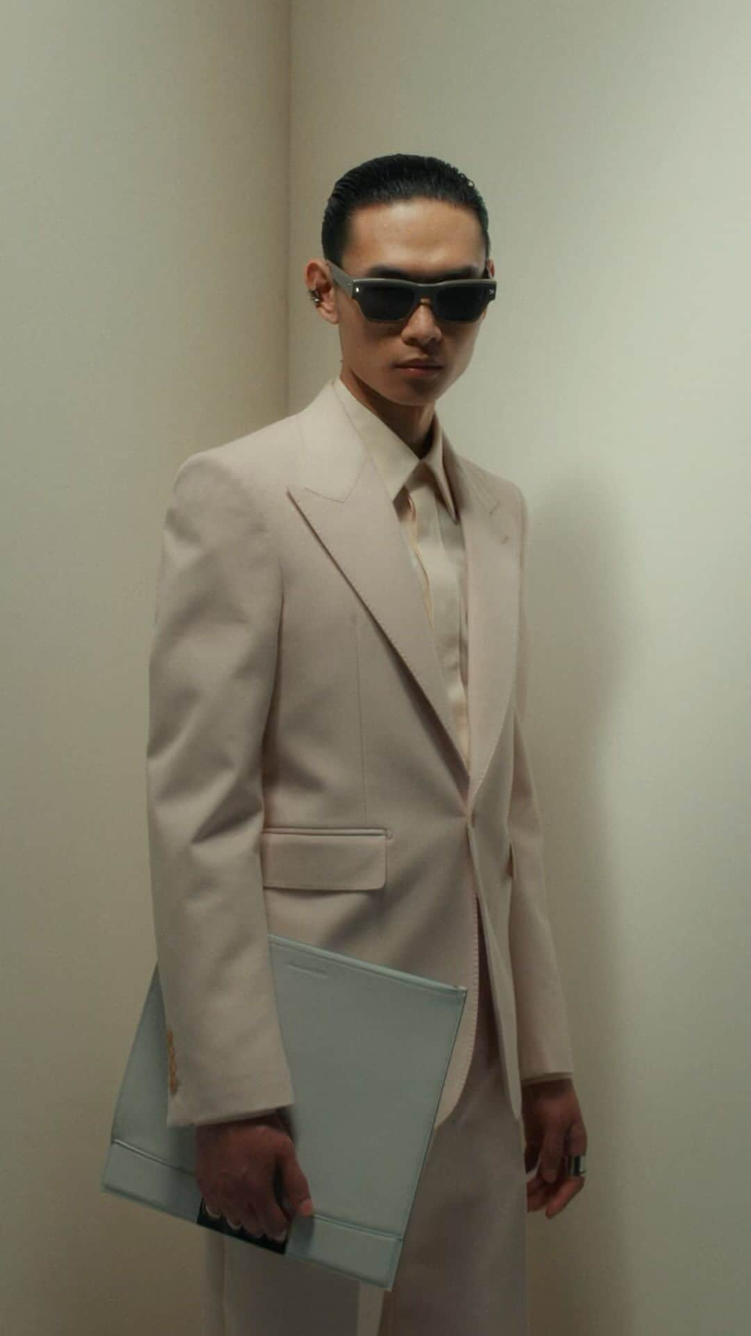 アレキサンダー・マックイーンのインスタグラム：「A single-breasted tailored jacket, cigarette trousers and a shirt in pale peach. Worn with the pale grey Grip pouch and Spike stud sunglasses.  Discover the #McQueenMenPreSS24 collection via the link in bio.  #McQueenEyewear  Video by @EbbaHult ⁣ Track: Indigo by Hit By A Rock⁣ Music Director: John Gosling」