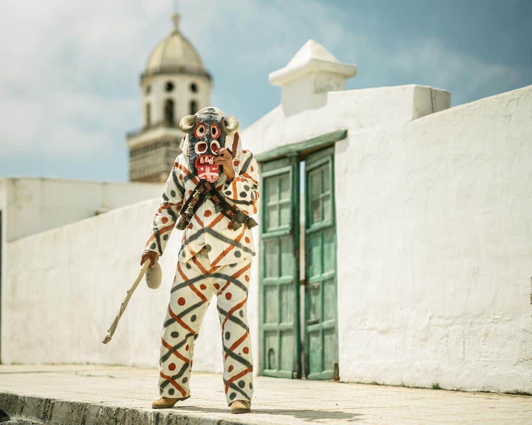 National Geographic Travelのインスタグラム：「Photo by Matthieu Paley (@paleyphoto) | Carmelo Delgado is one of the participants in the yearly Carnival festival of Los Diabletes de Teguise (the Little Devils of Teguise) on Lanzarote in the Canary Islands. This unusual celebration is said to have taken place every February since the 16th century in the town of Teguise. The participants—who wear masks, a painted outfit, and bells—carry sticks and walk the streets scaring passersby. I was lucky to meet Delgado during his mask workshop and to hear his stories. Of course, we stepped into the street for a portrait. | Discover what makes #Lanzarote so special @turismolzt  Learn more at the link in bio.」