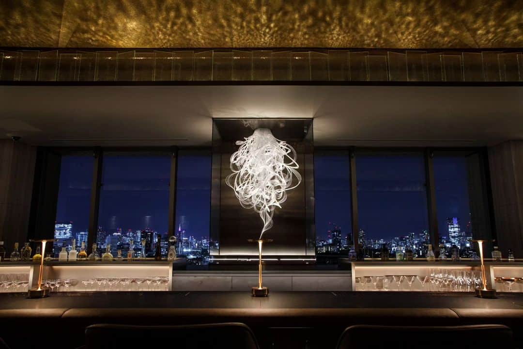 THE WESTIN TOKYO | ウェスティンホテル東京のインスタグラム：「ビール工場の煙突から立ちのぼる「煙」をデザインモチーフに“Smoke/Reflection/Surprise”というコンセプトのもと、幻想的な光が演出するスカイバー「エスカリエ」がグランドオープしました✨  最上階までたどり着いたゲストだけが、東京眺望とここだけにしかないカクテルとデザートを味わえる、そんなサプライズのある場所という意味を込めてフランス語の「階段＝エスカリエ」と名づけました。  シークレットドアを開ければプロンズを基調とした内装と東京の眺望が目の前に広がり、最上階からの心躍る驚きをご堪能いただけます。また、フロア窓際のソファーシートでは、東京の美しい夜景を眺めながらプライペート感あふれる時間をお過ごしいただけます。  世界中から集められたプレミアムスピリッツも数多くご用意。ミクソロジーの技術を駆使した季節のカクテルに加え、ワールドトップバーテンダー後閑信吾氏率いる世界最高のバーアワード「THE WORLD'S 50 BEST BARS」に輝く「The SG Club」がエスカリエのために創作した7種類のカクテル・ノンアルコールカクテルも揃えました。総料理長沼尻寿夫による大人のデザートもお楽しみいただけます。     詳細はプロフィールのリンクより🔗  Based on the concept of “Smoke, Reflection & Surprise”, the sky bar “Escalier” has opened its doors, along with an elegant and refined selection of cocktails✨  Only the guests who reach the top floor of The Westin Tokyo can enjoy the beautiful views and the cocktails and desserts exclusive to this bar, named after the French word for “Staircase”.  Open the secret door to this haven and reveal all of its surprises, from the bronze based interior design, to the sofa seats next to the windows where you can enjoy a private time while admiring the breathtaking night view of Tokyo.  "Escalier" also offers a wide variety of premium spirits from around the world and seasonal cocktails crafted using mixology techniques. To top it off, seven types of cocktails (including non-alcoholic mocktails) created exclusively for “Escalier” by the world-renowned bartender Shingo Gokan are also available alongside desserts created by executive chef Hisao Naganumajiri.  Join us for a night full of surprises and delight at The Westin Tokyo sky bar, "Escalier".  For more details please visit our bio link 🔗  #ウェスティンホテル東京 #ウェスティンホテル #ウェスティン #ホテル #日本 #東京 #改装 #グランドオープン #ホテルグランドオープン #バー #プレミアムスピリッツ #カクテル #後閑信吾 #スカイバー #眺望 #WestinTokyo #westinhotel #Escalier #skybar #cocktails #dessert #grandopening #mixology #skyline #views #mocktails #bronze #SingoGokan #Hisaonaganumajiri」