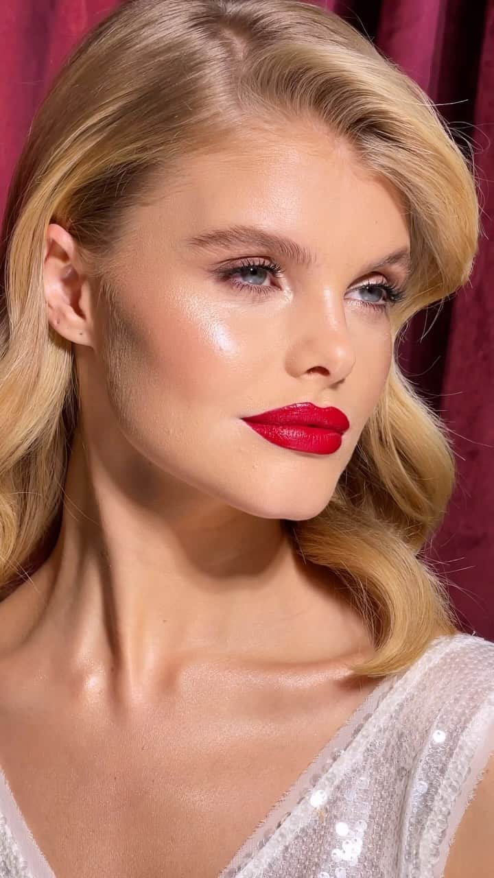 シャーロット・ティルベリーのインスタグラム：「✨💄FESTIVE RED LIPS💄✨  Radiant skin ✅ Sparkling champagne eyes ✅ A festive red lip ✅ Can you think of a more iconic holiday trio? Beautiful @megg_rutherford and my talented #TilburyProTeam artist @sofiamariamua serving up all the easy festive party inspo you need! ❤️ Full beauty breakdown below! ⬇️  #GetTheLook💄  💄by #TilburyProTeam artist @sofiamariamua  SKINCARE: Magic Serum Crystal Elixir Magic Cream Cryo-Recovery Eye Serum  COMPLEXION: Beautiful Skin Foundation - 4W Beautiful Skin Radiant Concealer - 4 Airbrush Flawless Finish Powder - 1 Hollywood Contour Wand - Fair/Mediun Beauty Light Wand - Spotlight Cheek to Chic - First Love  EYES: Super Nudes Easy Eyeshadow Palette Eyes to Mesmerise - Champagne The Classic - Classic Brown Pillow Talk Push Up Lashes! Mascara  BROWS: Brow Cheat - Taupe Brow Fix  LIPS: Lip Cheat - Kiss ‘N’ Tell Airbrush Flawless Lip Blur - Ruby Blur  #CharlotteTilbury #StepIntoMagic #CharlotteTilburyHoliday」