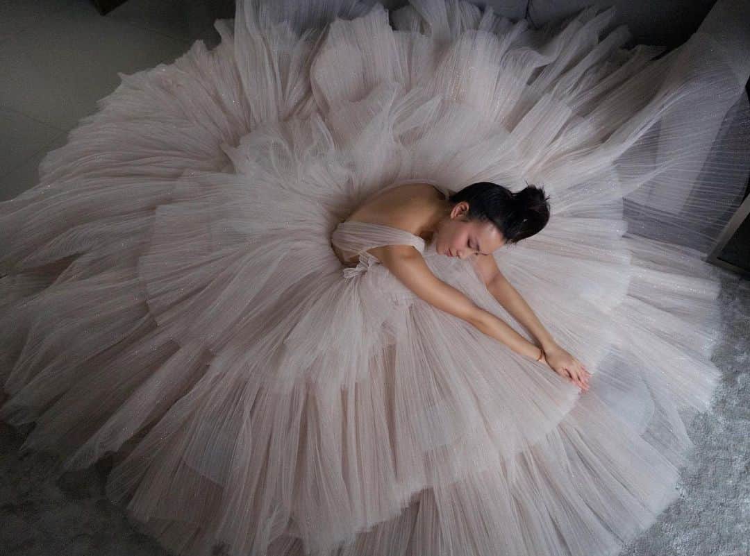 ソニアのインスタグラム：「Love is..when your partner stands up on a table with a camera he’s barely used before to take a photo of you sprawled on the floor in a floofy dress cos I insisted on a top down angle 🤣 Trust me when I say this @theivorybridal dress is almost as heavy as me!! . Many have asked if I used to do ballet (I have unusually long gangly arms for my height - some might mistake it to be graceful ballerina arms 🤣), but I’ve never attended a single class in my life. If you’ve seen me dance at the club, you’ll know I have no hand eye coordination. . I got to play dress up at home tho in this @nicolefeliciacouture gown thanks to @angjinyuan. She’s an amazing business woman and human being. If you ever need a gown once things go back to the new normal, do check out @theivorybridal 🦋✨ Watch out for part 2 of this photo series!  #gowns #bridal #stayhome」