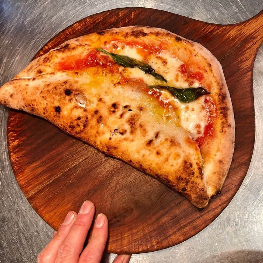 ポジリポのインスタグラム：「こんな形のPizzaを見たことありますか？ 【Luna Rossa ルナロッサ】 っていう名前のピッツァなんです  直訳すると【赤い月】の意味です。月光の赤い部分が“マルゲリータ”で、月陰の包み焼きの部分がリピエーノ（別名カルツォーネ）で出来ています。一枚のピッツァで二種類の料理が楽しめるナポリの定番ピッツァのひとつで、ナイフとフォークでいただくのがナポリ流ですよ。  ２枚目の写真はルナロッサを焼く直前。一枚のピザ生地から月の形に仕上がります。 ピッツァイオーロって器用ですし、ネーミングもおしゃれ！！ ・ ・ Have you seen Pizza of such a form? 【Luna Rossa】 It is the pizza of the name to say this  It is a meaning of 【the red moon】when I translate it literally. A red part of the moonlight is "Margherita", and the part of another is made of ripienos (Calzone) in a month. In one of the basic pizzas of Naples that can enjoy two kinds of cooking with one piece of pizza, it is a Naples style that has with a knife and a fork.  The second piece photograph burns Luna Rossa just before that. I am finished in the form of the month from one piece of pizza dough. I am skillful with Pizzaiolo , and the naming is stylish, too!」