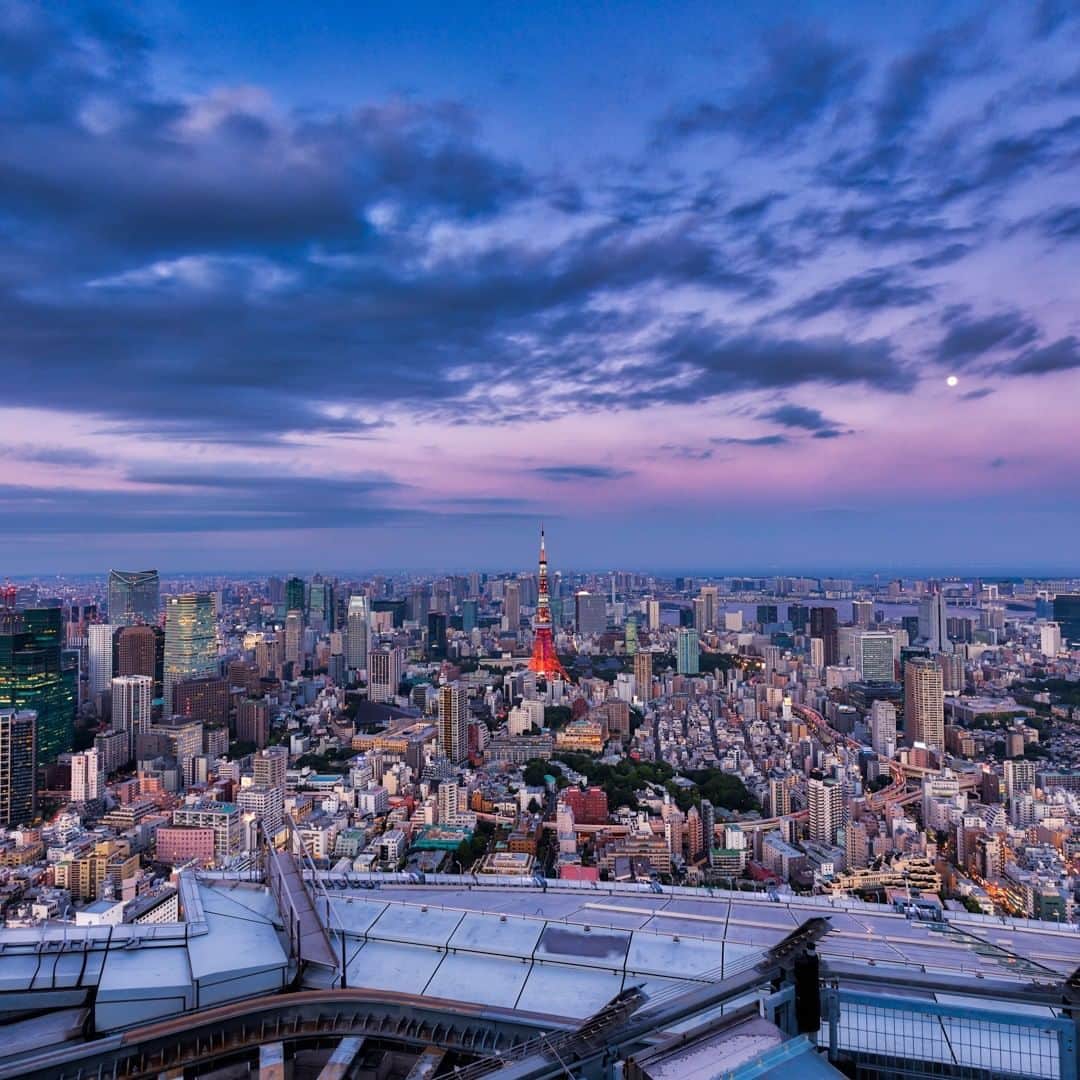 Tokyo City View 六本木ヒルズ展望台のインスタグラム：「📸六本木ヒルズ展望台 東京シティビューから、絶景画像をお届け中！  ある夏の日、ぶどう色の雲が広がる東京の夕方の景色。右の空に小さな白い月が見えますが、明るい街はまだ夜を迎えたくなさそうです。😊 #StayHome #うちで過ごそう #おうち時間 #東京シティビュー #tokyocityview #休館中の展望台 #SNSで楽しむ展望台 #荒谷良一」