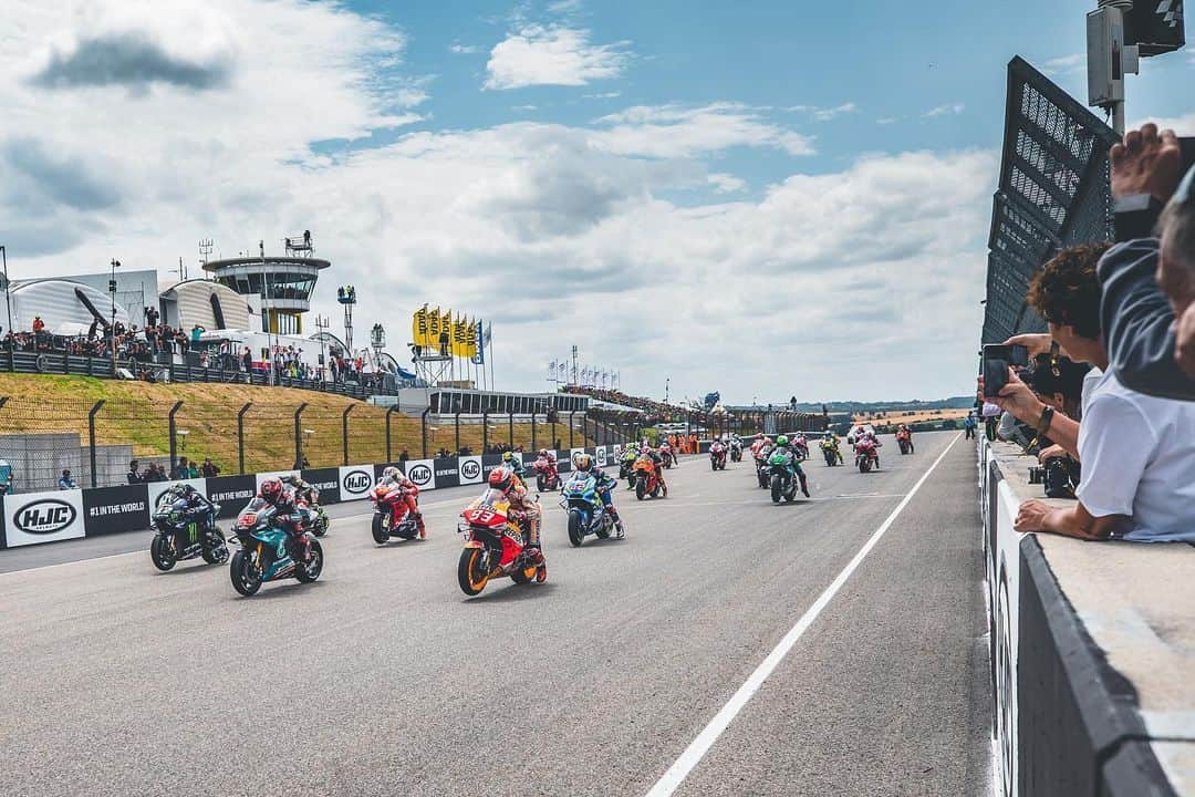 レプソル・ホンダのインスタグラム：「#ThrowbackThursday - Through The Lens - @polarityphoto ⠀⠀⠀⠀⠀⠀⠀⠀⠀ When you only have once chance to capture the start of a race, where do you go?! Of course, there is no right or wrong answer to this question but it is something that as a MotoGP photographer I ask myself every time we race. The race start is a great opportunity to catch the bikes altogether and to try and convey the amazing spectacle of a full grid of riders charging into the first few corners. On this occasion I wanted to shoot something different that the normal Turn 1 or 2 shots so I decided to use a wide angle lens along the pit wall and the result turned out pretty good. Using continuous focus mode and a fast shutter speed I captured the moment the lights went out and I remember being very grateful that I had my ear plugs in as the bikes launched and shook the ground as they thundered off the line!  1/2500 sec. f/5  35mm ISO 100」