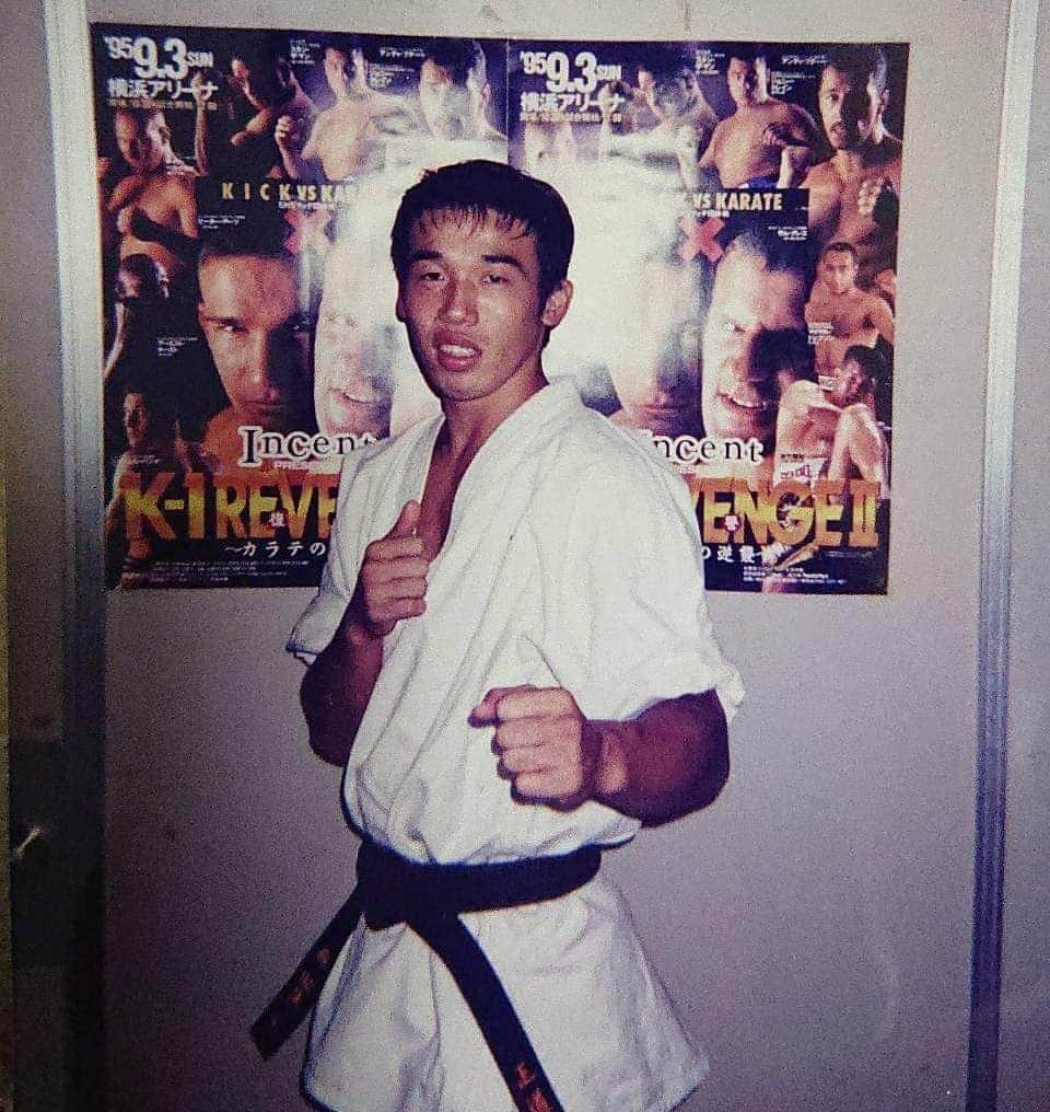 のインスタグラム：「俺のデビュー戦大会「K-1REVENGE Ⅱ」のポスターが貼られてるから、デビュー前かデビュー直後の写真かなぁ。  プロ練に参加してまだ半年、空手の試合しかしたことがなかった俺のグローブをはめての初めての試合がK-1で、横浜アリーナで、相手はパトスミやった。  新空手とかアマチュアキックの試合とかで経験積まさせてくれへんの？いきなりですか？  つけられたリングネームが「ムサシ」  アンディ・フグとスパーリングで互角に渡り合うとんでもない新人がデビューとか煽られたな～。 毎日アンディにボコボコにされとったっちゅーねん。  試合前日も緊張と恐さで眠れず、ホテルの部屋でシャドーしてた。  このデビュー戦がキャリアの中で1番緊張しました。  #武蔵 #k1 #空手 #karate #kickboxing」