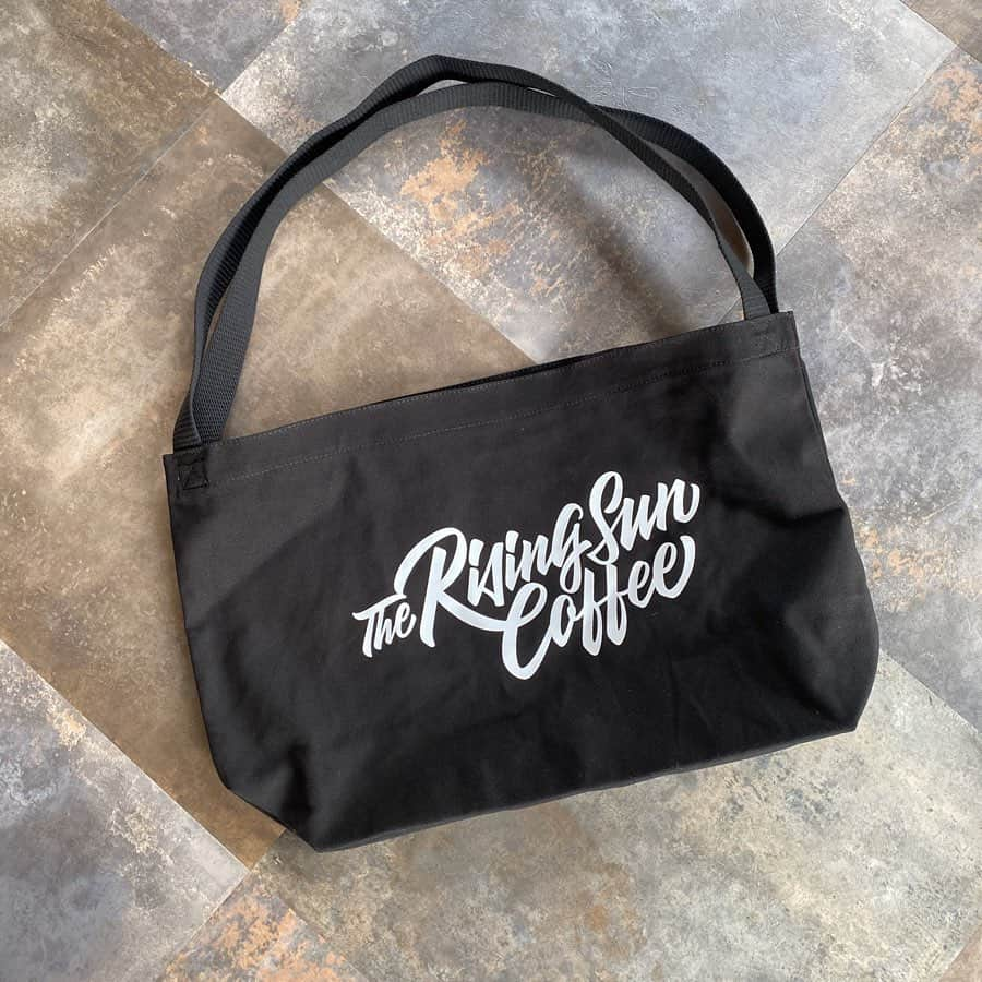 坂口憲二（THE RISING SUN COFFEE）さんのインスタグラム写真 - (坂口憲二（THE RISING SUN COFFEE）Instagram)「◆GOOD MORNING COFFEE‼︎◆ .  TRSC ORIGINAL BLACK TOTE BAG .  昨年製作して好評だった、オリジナルトートバッグをアップグレードして再製作しました。今回はフロントにTRSCスクリプトロゴを落とし込み、バックには小さくカタカナロゴ、最も特徴的である持ち手(紐)部分には前回同様、丈夫な紐を使い、ストレスなく使える仕様となっております。  販売は本日正午より、オンラインストアにて開始します！  #coffee #coffeebeans  #coffeeroaster  #coffeelab  #coffeeandsurfing  #coffeetime  #coffeelover  #coffeebreak  #coffeeshop  #coffeestand  #coffeeholic  #coffeehouse  #coffee_inst  #coffeemaker  #coffeeshops  #coffeecoffeecoffee  #coffeenclothes  #coffeeaddict  #coffeeculture  #coffeemorning  #coffeemag #specialitycoffee  #black #totebag  #new #TRSC」5月27日 8時06分 - therisingsuncoffee