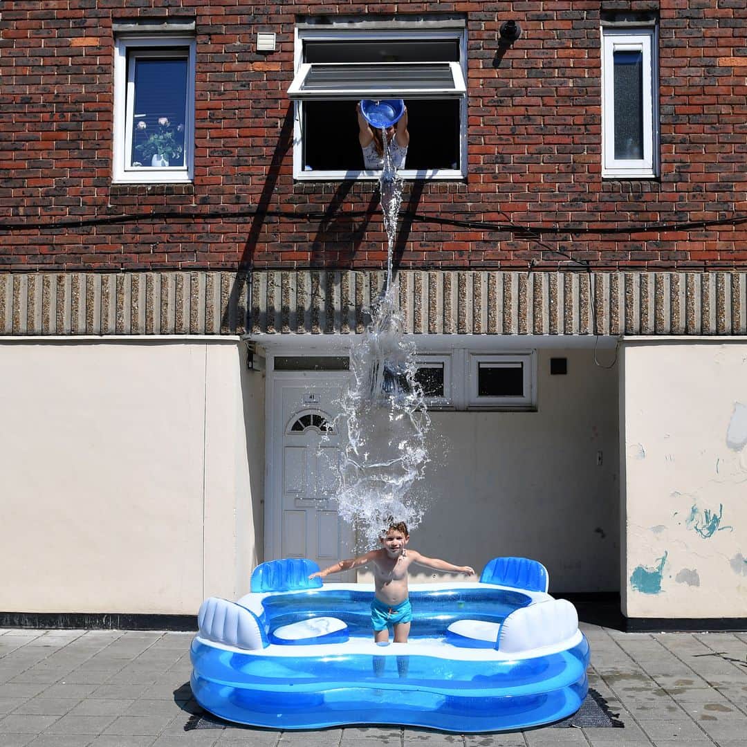 AFP通信さんのインスタグラム写真 - (AFP通信Instagram)「AFP Photo 📷 @justintallisafp - Kamila fills up a paddling pool by throwing water from an upstairs window over her son, five-year-old Luca, as he stands in it in Hackney, east London as temperatures in Britain soar.⁣ .⁣ Just days after lockdown ended and European travel restrictions were lifted, many were staying home in the cool as a heatwave hit the continent with temperatures touching 40 degrees Celcius. Britain was bracing for a flood of visitors to its beaches with the heatwave expected to last until Friday and temperatures set to climb into the mid-30s in the south and centre of the country. #heat #heatwave」6月26日 22時19分 - afpphoto