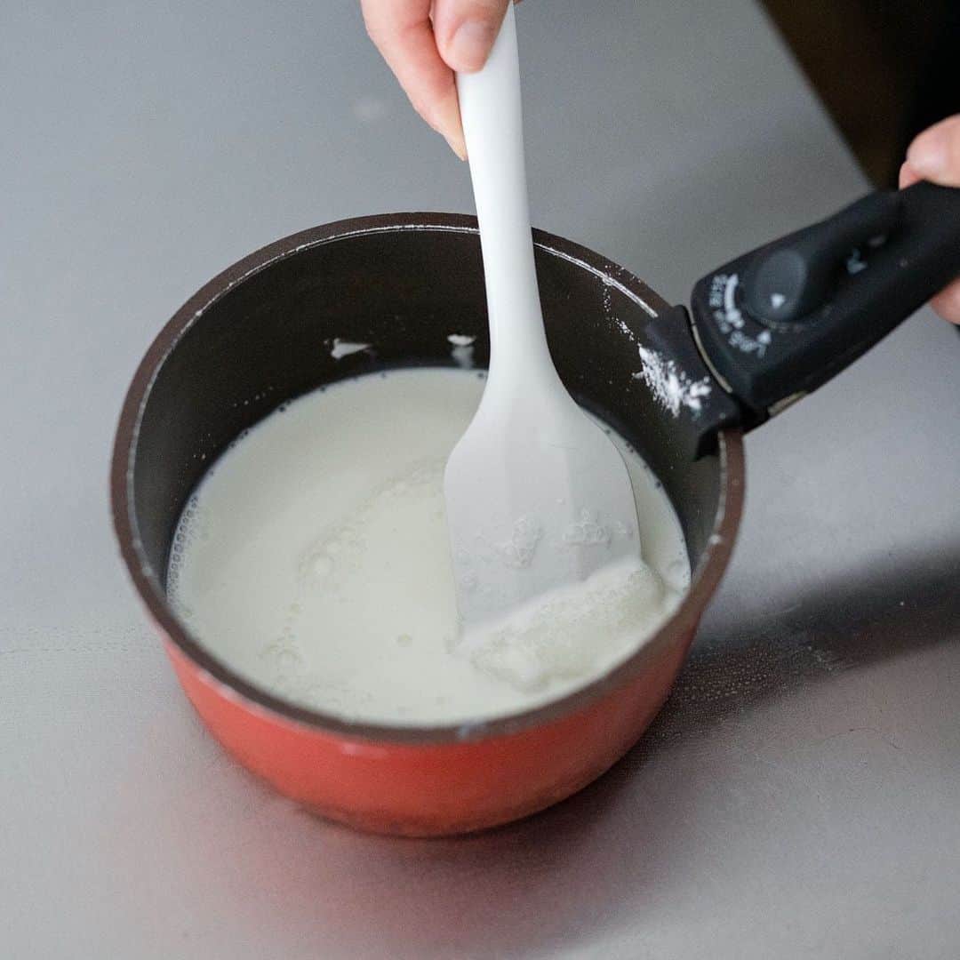北欧、暮らしの道具店さんのインスタグラム写真 - (北欧、暮らしの道具店Instagram)「材料は片栗粉・牛乳・砂糖だけ。みずみずしい「癒しのミルクもち」レシピ . - - - - - - - - - - - - OYATSUYA SUNの梅澤さんに スキマ時間でも、さっと作れる 簡単おやつレシピを教えていただきました♪  今回ご紹介する「ミルクもち」は、 わらびもちと白玉のあいだのような、 ぷるぷるとした食感が楽しいおやつ。  疲れを癒してくれるような、優しい味わいです。 . - - - - - - - - - - - - つるつるでプルプルな、癒しのおやつ 片栗粉でつくる「ミルクもち」 - - - - - - - - - - - - . 【材料（2〜3人分）】 . 片栗粉…35g グラニュー糖…25g 牛乳…250ml . お好みで、黒蜜・きなこ・黒ごまやメープルシロップなどをかけて食べると美味しいです。 . ＜スムーズにするための下準備＞ ・あらかじめ氷水をいれたボールを準備しておくと、 スムーズにできます。 . 【作り方】 . ❶ 片栗粉・グラニュー糖を小鍋に入れ、牛乳を注ぐ。 ダマがなくなるまで、よく混ぜ合わせる。 . ❷ ダマがなくなったら、鍋を火にかける。 最初は中火で、とろみが出てきたら弱火にし、 焦げないようにゴムベラで絶えず混ぜ続ける。 とろみが出てくると一気に固まりはじめるので、 混ぜる手を止めないようにするのがポイント。 もちもちとしたひと塊りになったら、 さらに1分ほどよく混ぜて火を止める。 . ❸ おもちをスプーンですくいとり、 氷水をはったボウルの中に落とす。 このときスプーンごと氷水の中に入れ、 ボウルの中でおもちをこそげ落とすと、上手にできます。 . ❹ よく冷えたらザルにあげ、 水気をきって器に盛り、お好みで黒蜜やきなこ、 ごまなどをかけて完成です！ . 白玉のようにフルーツポンチに入れてみたり、 アイスクリームやあんこと一緒に 食べたりしても美味しいですよ。 ぜひいろいろアレンジしてみてくださいね。 . - - - - - - - - - - - - 梅澤さん： . 「コツはきちんと火を通すこと。 粉っぽくならず、美味しく仕上がります。  スプーンですくうので、僕がつくっても 絶対にきれいな丸には仕上がりません（笑）。 けれどそれは、おうちで作るからこそ 味わえる魅力でもあると思います。  決してお店では出てこない、 そんな不恰好さも愛嬌があって、 どこか愛おしいおやつです。  できたてが一番美味しいのですが、 水と一緒にタッパーに入れて冷蔵庫で保管すれば、 翌日食べることもできますよ」 . #kitchen#kitchendesign#kitchenware#OYATSUYASUN#recipe#レシピ#キッチン#料理#おやつ#おうち時間#家おやつ#おもち#ミルクもち#シンプル#シンプルライフ#シンプルデザイン#お買い物#暮らしを楽しむ#日々の暮らし#北欧#暮らし#北欧暮らしの道具店」6月11日 16時32分 - hokuoh_kurashi