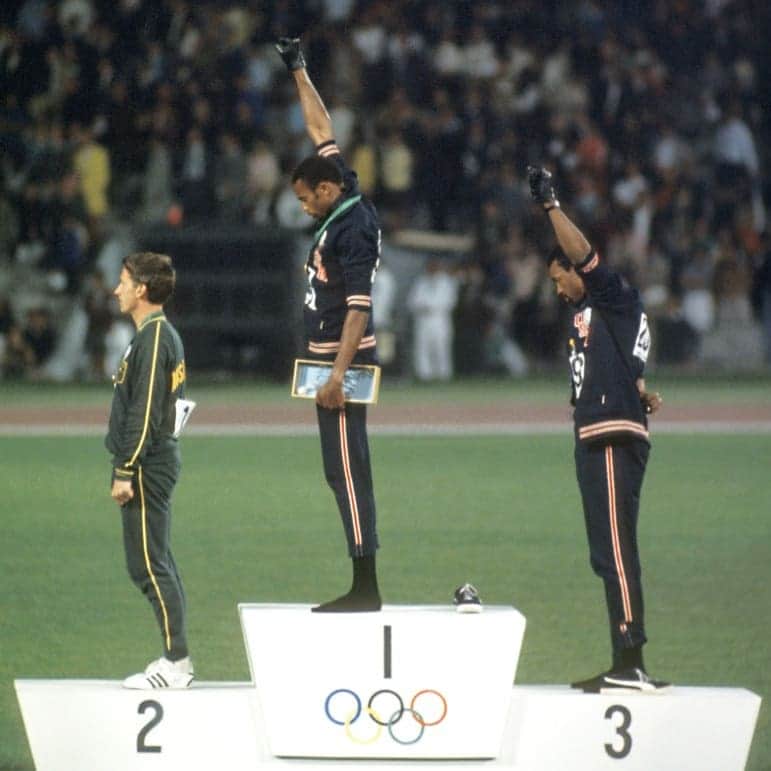 ガス・ケンワージーのインスタグラム：「I think this is one of the most powerful images in the history of sport. US Olympians Tommie Smith (Gold) and John Carlos (Bronze) raise gloved fists on the podium at the '68 Games to stand up to the racial injustice that Black people were (and still are) facing in the US and around the world. They took off their shoes and stood in socks to bring attention to the plight of Black poverty back home, wore beads around their neck to protest lynchings and, along with Peter Norman the Australian who won silver, wore patches of the Olympic Project for Human Rights - a group that Smith and Carlos helped organize as a way to reflect their Black pride and social conciousness. Norman was essentially cancelled by the Australian Olympic Committee for standing in solidarity with Smith and Carlos. Despite qualifying for multiple subsequent Olympic Games as the #1 Australian in the world the country instead chose not to send a sprinter at all and refused to recognize his accomplishments until 2012, six years after his death. Smith and Carlos were booed off the podium, kicked out of the Games, suspended from Team USA and went home to death threats. 48 years later when Colin Kaepernick peacefully knelt to protest racial injustice and police brutality in the US he was blackballed from the NFL. White people, now it is all of our chance to be a Norman and to stand in solidarity with Smith, Carlos, Kaepernick and the entire disenfranchised Black community. If you can march, march! (If you're in LA join me on Sunday - see slide 3). If you can donate, donate! (See slides 4 & 5 for good suggestions on where to give your money - thanks @stephseemsok for the list). If you can't do either of those things then educate yourself! I suggest starting by watching the Racial Wealth Gap episode of "Explained" on @Netflix, it takes 15 minutes and it's incredibly eye-opening. Have difficult discussions with family members who may not understand the Black Lives Matter movement. Sign petitions, make calls and write e-mails to demand justice and help create change! Do anything but don't do nothing. All lives will matter when Black lives matter. ✊🏻✊🏼✊🏽✊🏾✊🏿」