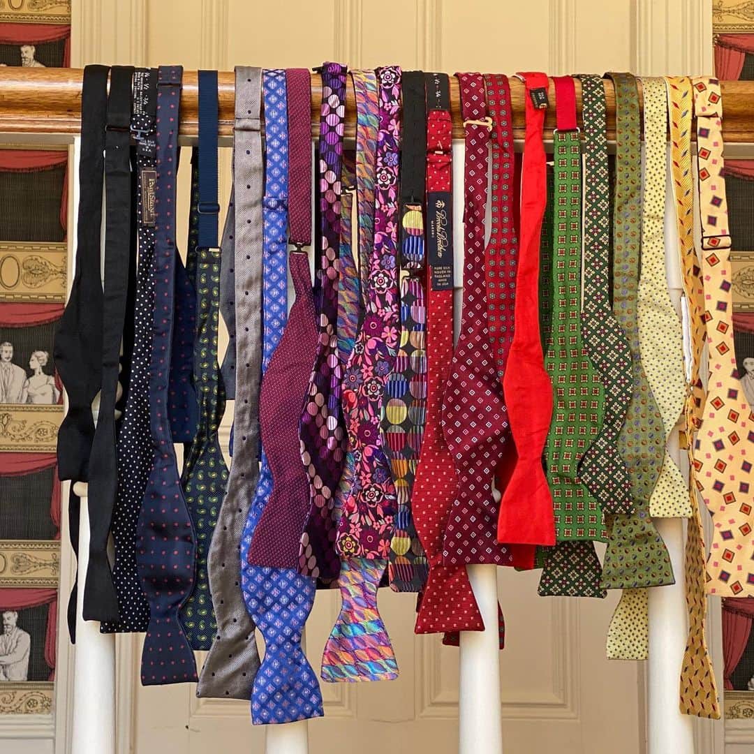 スティーヴン・フライさんのインスタグラム写真 - (スティーヴン・フライInstagram)「A selection of bow ties hanging from a banister today. Overdoing it a spot to give every one of them a whole day to themselves, so these bows must take their bows as a chorus line, an ensemble. They’ve even got a theatre audience in opera boxes watching them from the wallpaper. Who knows where I got them all. Some don’t have tags or labels to help jog my memory. But there are representatives here from Frederick Theake (20 years since sadly they were dissolved as a business), Brooks Brothers, Hilditch & Key, Liberty, Harrods, Tie Rack, a company unknown to me whose logo is a bugle or post-horn, Hackett, Paul Stuart, and Paul Smith. I've broken a rule and added a made up rose tie from @lecolonel_official because it's so lovely swipe left for Pic 2  The little video (swipe again) is of me tying the green Hilditch & Key around my neck. As I comment in it, it’s easiest to start by practising on the leg. Most of us will find that just below the knee is the best place, usually corresponding in girth to the neck. I hope some of you might find the video helpful: I do appreciate it’s a fiddly business: impossible to get the camera in to show the way one end is pushed through to complete the knot. it’s all about feel really.  Doctors, surgeons, vets and dentists used to favour the bowtie. Unlike conventional neckties they can’t dangle down into a patient’s face or open gizzard and guts. Those days are mostly past, though costume designers in TV dramas will usually pick them to denote an old-fashioned, often private, physician. Otherwise bowties are most associated in the public mind with Winston Churchill and - for my generation – the wonderful Frank Muir and fearsome Robin Day. Who else wears them? Takes a bit of courage. So easy to be dismissed as pompous, self-regarding and, not to put too fine a point on it, something of a dick. So I tend to stroke mine fondly every now and again but not much more than that. Of course, one use is as a substitute for plain black when a dinner jacket (or tuxedo as Americans call them) is required.  Oh and you do NOT have permission to take the phrase “I tend to stroke mine fondly every now and again” out of context. Got it? Good.」6月16日 13時40分 - stephenfryactually