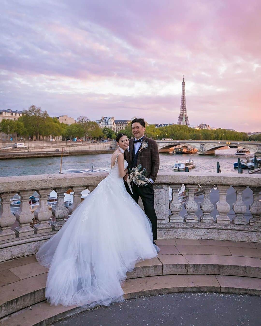 25ans Wedding 公式 Bridesのインスタグラム：「今日もmayus_sさんのフォトをリポスト📸 セーヌ川の向こうにエッフェル塔がそびえる、パリの魅力が詰まったロケーションで寄り添うふたりがとっても素敵な一枚☺️ふんわり広がるドレスが夕焼け空によく似合います。」