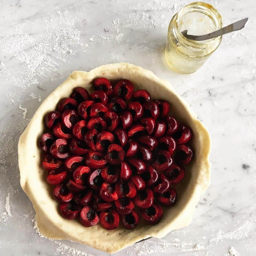 福田里香さんのインスタグラム写真 - (福田里香Instagram)「🍒cherry pie🍒 チェリー🍒ピッターで 種を取り除いた🍒で、チェリーパイ。  隠し味は、びん底に残っていた 🥄２すくいほどの四季柑のコンフィ。 柑橘のマーマレードは 🍒の酸味のなさを補って よいアクセントになります。  コンフィをパイ生地に塗りつけたら 🍒を敷き詰めるように並べ 溶かしバターと砂糖を 霜が降りたようにトッピング。 🍒ばら科の果物 🍋柑橘系の果物  アーモンドプードルがあれば フィリングを作って 🍒の下に敷くのも、間違いない相性。 チェリー＆アーモンド、おいしいよね。 🍒ばら科の果物 🌳ばら科の木の実  #cherrypitter  #cherrypitremover #cherrypie」6月18日 7時07分 - riccafukuda