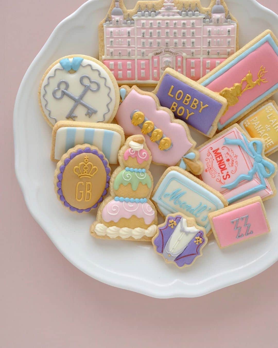 KUNIKAのインスタグラム：「THE GRAND BUDAPEST HOTEL cookies 🗝🏨⛷💀🦌🌨🧁🚠🛠🛎🧳﻿ ﻿ 好きな映画のクッキーを作るシリーズ第2弾。﻿ グランド・ブダペスト・ホテルをテーマに作りました🤵🏼﻿ ﻿ MENDL'Sの店内のロケ地はドイツの古都ドレスデンにある世界一美しい牛乳屋さん、ドレスナー・マルケライ・ゲブリューダー・プフント。﻿(ちなみにギネスにも認定されているそう!) 3年前のクリスマスに一度足を踏み入れました。﻿ 息をのむほど美しい店内はなんと撮影禁止なので、外のウィンドウディスプレイだけが思い出の写真。﻿ わざわざドレスデンまで行って、あんなにも美しい店内を記録できないという、生きてきた中で1番の衝撃でした。﻿ こぞって華やかな写真を載せてもらうことに注視している現代において、そのポリシーが尊く、かっこよくて...﻿ 写真に収められないからこそ、ずっと心の中に残るんだなぁ、と。﻿ 映画の中では一瞬しか映らないけど、それもまた良い ( ´◡` )﻿ ﻿ #artofkunika ﻿」