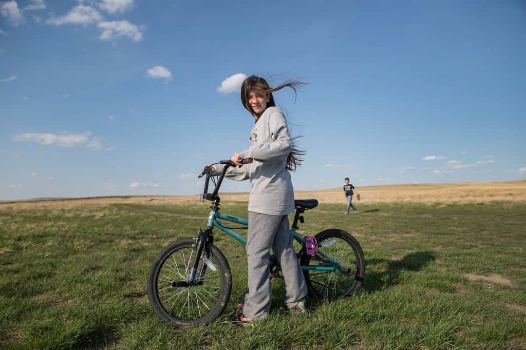 National Geographic Travelさんのインスタグラム写真 - (National Geographic TravelInstagram)「Photo by @amivitale | Children welcome summer in east Montana after a long winter. A few years ago, there was an explosive growth from the oil boom of North Dakota that spread to the small Montana border towns and caused an influx of workers and shortage of space. Rent here for a small trailer cost more than an apartment in New York City. Today the oil boom is over and North Dakota’s oil industry is quiet again.  Learn more about the world by following @amivitale. @thephotosociety #montana #bicycle #children #biking」6月24日 9時04分 - natgeotravel