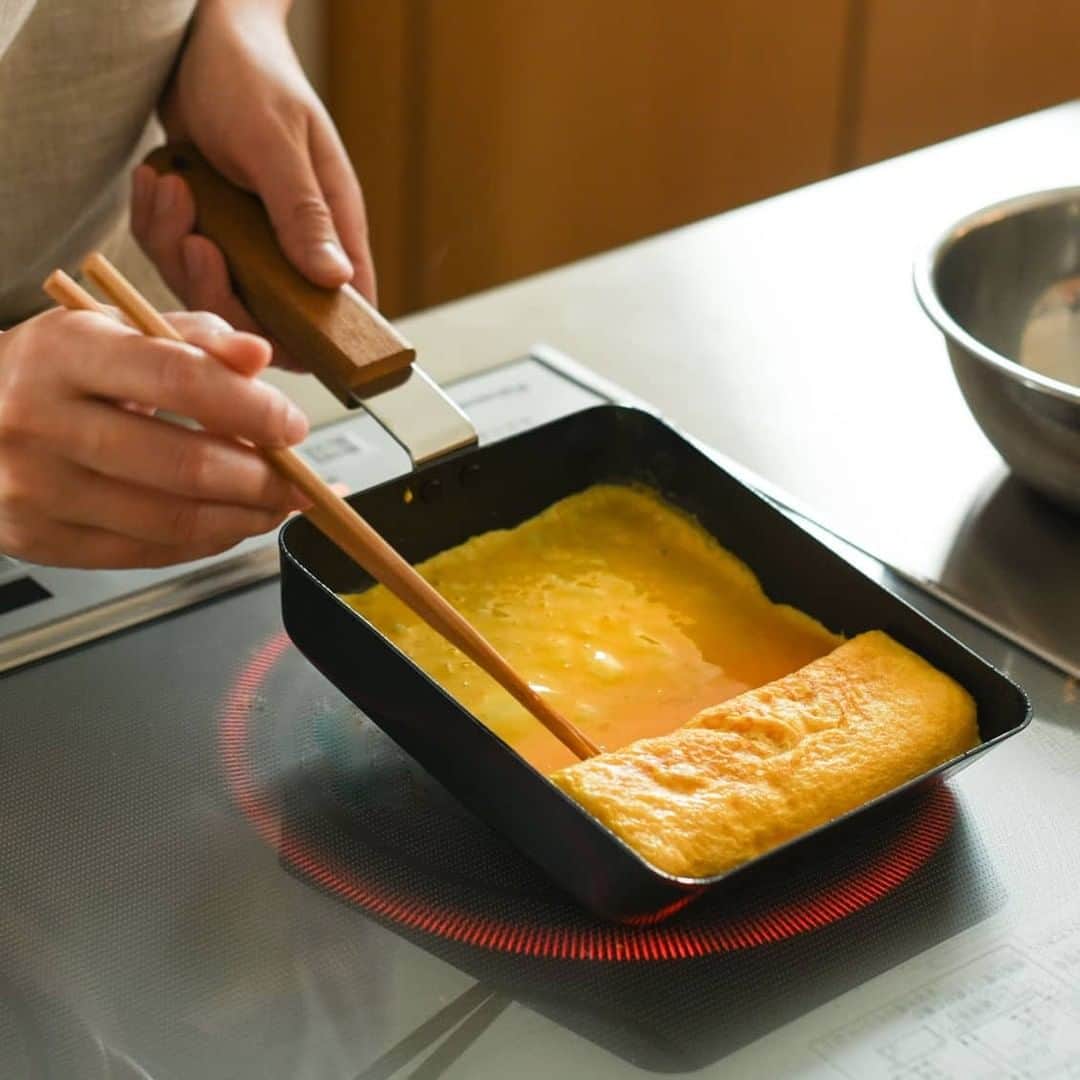 北欧、暮らしの道具店さんのインスタグラム写真 - (北欧、暮らしの道具店Instagram)「朝ごはんからお弁当までこれひとつ！お料理上手になれる「玉子焼フライパン」 . - - - - - - - - - - - - スタッフも愛用中で、その使い心地はお墨付き。 ambaiのフライパンなら、 コツいらずで、綺麗でおいしい 玉子焼ができるんです◎  蓄熱性の高い鉄を使用しているので 均一に熱が加わり、卵をふっくら 焼き上げることができるという優れもの。  持ち手はチーク材でできているので、 直火でも熱くなりすぎず、 安心して使えますよ。  焦げやこびりつきを防ぐ 「ファイバーライン加工」が施されているから、 鉄なのにくっつかないのが嬉しいポイントです♪  忙しい朝はこれひとつで、玉子焼はもちろん、 ソーセージや野菜を炒めなど、 いろんな調理に役立ちますよ。  休日は、出来上がったばかりの ふわふわの厚焼き卵を、早速パンに挟んで。 喫茶店のような「厚焼きたまごサンド」を 楽しむのも良いですね◎  見た目がおしゃれだから、 使わないときはフックにかけて。 つい見せる収納をしたくなる可愛い佇まい。  直火もIHもOKです♪ ぜひお試しくださいね。 . - - - - - - - - - - - - ambai/玉子焼・卵焼きフライパン（角） . ▶︎お買いものはプロフィールのリンクからどうぞ→@hokuoh_kurashi . #kitchen#kitchendesign#kitchenware#food#foodstagram#ambai#フライパン#玉子焼#卵焼き#卵サンド#キッチン#キッチン雑貨#食器#台所#ごはん#朝ごはん#ランチ#お弁当#料理#シンプル#シンプルライフ#シンプルデザイン#暮らしを楽しむ#日々の暮らし#北欧#暮らし#北欧暮らしの道具店」7月1日 21時01分 - hokuoh_kurashi