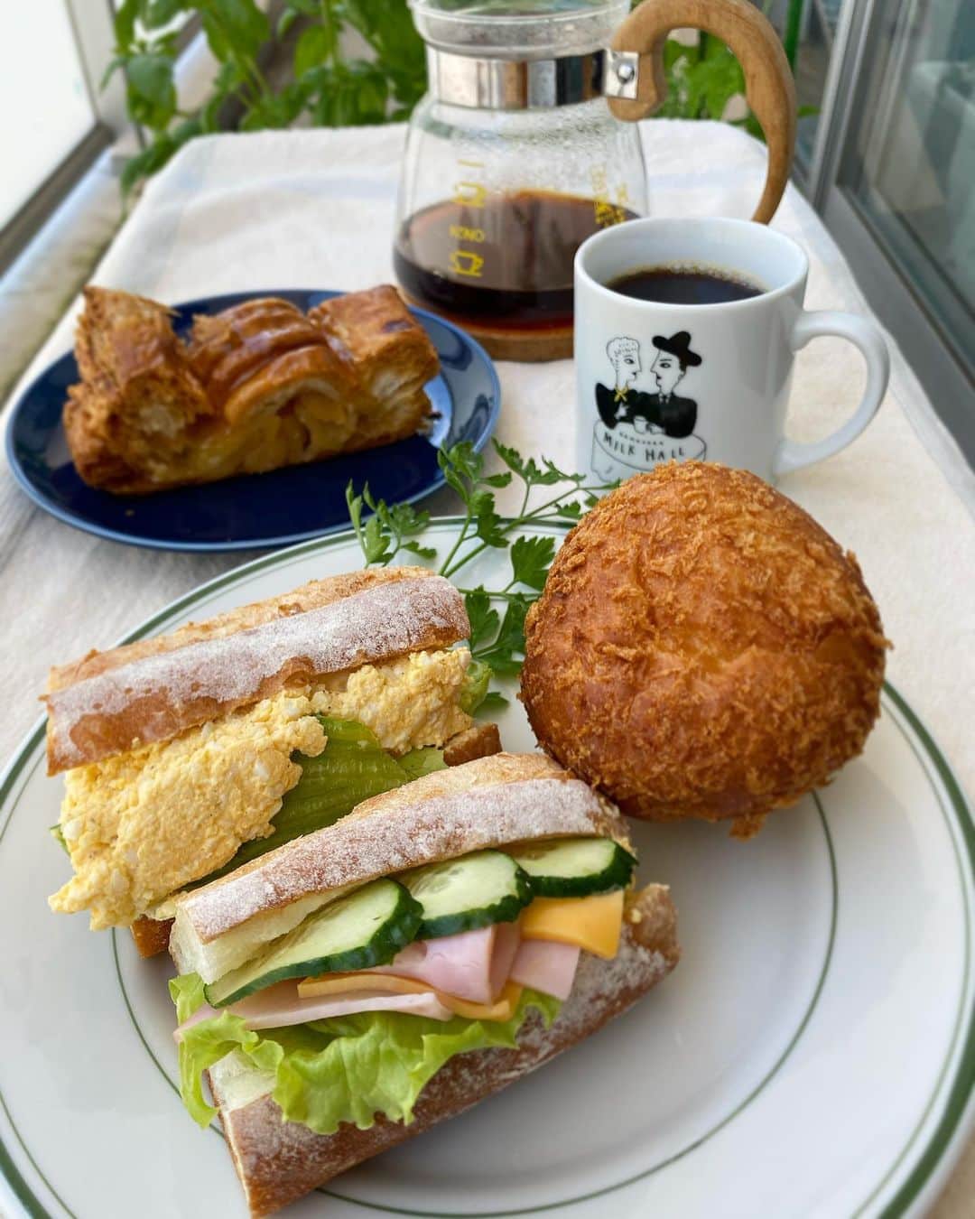クボタマサヒコのインスタグラム：「🥪 ひさびさに初夏らしくて気持ち良いので、たまには人様の作ったものを欲して半外セッティングで食べてみる。  いつもの市場で夏野菜(溢れてた)と地産の鰯に夏酒と島酒買って夜は酢締めで一杯いけるといいな🐟🍶  まずは会議とマスタリング…！(これも初リモート挑戦)  #ブレドール葉山 #coffee #鎌倉ミルクホール #夏野菜 #鰯 #夏ヤゴ #泉橋酒造 #夏酒 #久米仙 #泡盛 #島酒 #okinawa #🍅 #🥒」