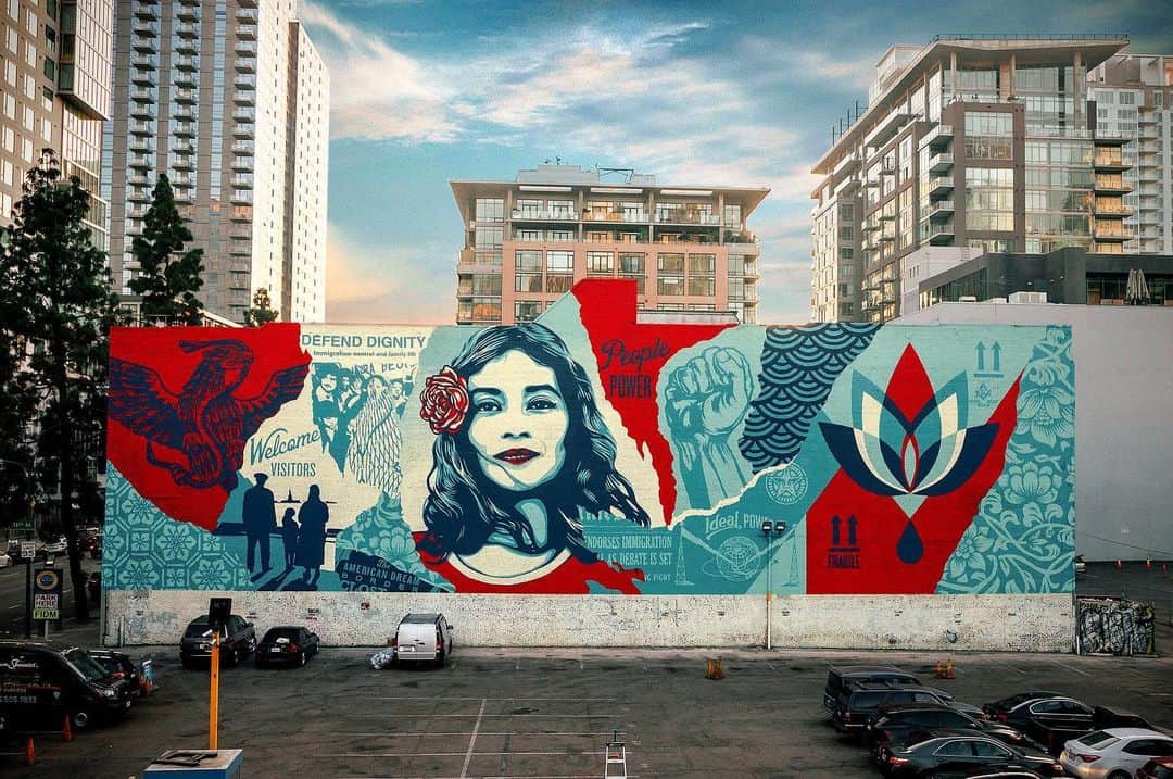 Shepard Faireyのインスタグラム：「Today, I'm throwing it back to one of my largest murals in LA, which I completed last November, in partnership with @brandedarts, @oti.official and my mural crew. This "Defend Dignity" piece was created to inspire sensitivity toward our fellow human beings and the planet itself. The central image, one of three that I created for the WE THE PEOPLE series, is a portrait of Maribel Valdez Gonzalez, a Texan of Mexican descent who was photographed by @ari.mejorado. I collaborated with Arlene, who works on immigrants' rights, to create this image as a symbol of hope, dignity, and humanity. The bleeding lotus is a symbol of the beauty and fragility of our planet. ⠀⠀⠀⠀⠀⠀⠀⠀⠀⁣⁠⠀ One of the most significant ways we can defend dignity and protect humanity in this country is to make our voices heard and VOTE this upcoming November. I created MAKE AMERICA SMART AGAIN with my wife, @amandafairey in 2016 as a call to action for Americans to be more involved in our democracy. Stay informed and follow us on @dumbisovermasa! As always, thanks for caring.⁠⠀ -Shepard⁠⠀ ⠀⠀⠀⠀⠀⠀⠀⠀⠀⁣⁠⠀ 📷: @jonathanfurlong #throwback #tbt #obey #obeygiant #shepardfairey」