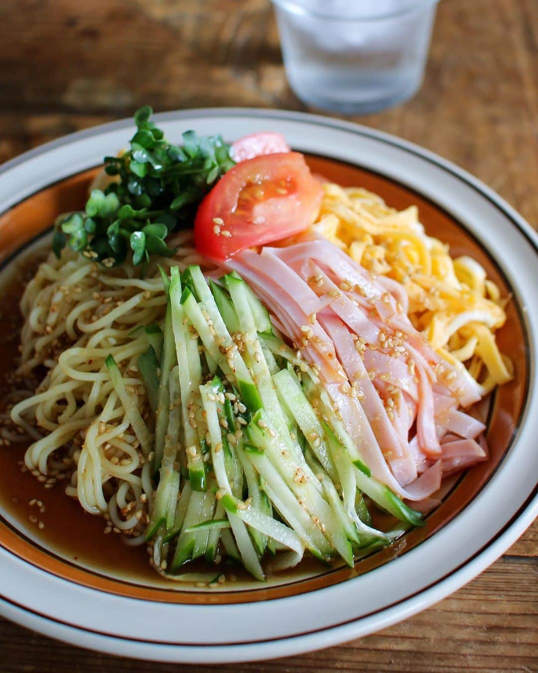 かおしさんのインスタグラム写真 - (かおしInstagram)「今日の昼休みにダッシュで帰って作ったごはんはこちら💁‍♀️ #冷やし中華はじめました ・ 一見普通の#冷やし中華 なのだけれど、実はちょっと変わり種。 麺は焼きそば麺、タレは『焼肉のタレ＋お酢』で作った冷やし中華なのであります👩‍🍳 だって、冷やし中華のタレってなかなか常備してないし…、だったら家にあるもので作るしか‼️ そう、それが#在宅楽飯 ✨💃 これすごく美味しいのでオススメです‼︎😃 ・ 【#焼肉のタレde冷やし中華 】 ・ ●材料(2人分)● 焼きそば麺(細めのもの) 2玉 きゅうり 1本 ハム 5〜6枚 カイワレ 1パック トマト 1個 ◎卵 2個 ◎片栗粉 大さじ1 ◎水 大さじ1 ★焼肉のたれ 100cc ★酢 50cc ★いりごま 大さじ1 辛子 お好みで マヨネーズ お好みで ・ ●作り方● ①◎をボウルに入れてよく混ぜる。フライパンを熱してサラダ油(分量外)をひき、1/2量を流し入れ、固まったらひっくり返して軽く焼き取り出す。残りの1/2も同様にする。取り出した薄焼き卵をくるくると巻き、包丁で細く切って錦糸卵にする。 ②ハム、きゅうりを細切りにする。トマトはくし形切りにし、カイワレは根元を切る。★の材料を混ぜ合わせてタレを作る。 ③鍋にお湯を沸かし、沸騰したら焼きそば麺を入れ、ほぐしながら45秒〜1分ほど茹でる。ざるにあげてお湯を切り、流水で粗熱を取ったら、そのざるに氷を入れ、麺とよく混ぜて冷たく冷やす。 ④お皿に麺をのせ、きゅうり、ハム、錦糸卵、トマト、カイワレを盛り付ける。★のタレを回しかける。好みで辛子やマヨネーズを添える。できあがり。 ・ 「えっ⁈焼肉のタレで冷やし中華ってどういうこと⁈想像できない‼︎🙄」と思った方にこそ、ぜひ試していただきたい😎 焼肉のタレって、様々な野菜や果物が入っていて、言うなれば旨味のミックスジュース(😂)みたいなものだし、適度に粘度もあるから麺や食材にしっかり絡むの。 「冷やし中華はあっさりしてるからあんまり…😓」な男性陣にもぜひ食べてみていただきたい、しっかり味の美味しい冷やし中華になっております✨🍜 😆 ・ ちなみに愛用の焼肉のタレは、昨日ストーリーズに載せた#ダイショー秘伝焼肉のたれ なのだけれど、皆様のイチオシの焼肉のタレがあれば知りたいな(ローカルな商品とかも気になる🤤)。 ・ あと、麺‼︎ 焼きそば麺は油がまぶしてあるので、必ず茹でてから使用するよ👩‍🍳 沸騰したお湯にチャポンと入れて10秒ほどしたら箸でほぐし(すぐほぐれる)、そこから30〜40秒ほど茹でます。 茹ですぎ厳禁🈲⚠️ 粗熱をとったらざるの中で氷と麺をガシガシ混ぜてしっかり冷やしてね👩‍🍳 冷やし中華はぬるいとイマイチだから🤪 #マルちゃん焼きそば みたいな3玉入りのタイプが細麺でちょうどイイ👍 ・ 簡単で美味しいので、ぜひ作ってみてね💁‍♀️ ・ #焼肉のたれレシピ #焼肉のタレレシピ #お助けメニュー #お助けレシピ #テレワーク飯 #冷麺 #焼肉のたれ #焼肉のタレ #簡単レシピ #私のおいしい写真 #foodporn #onthetable #foodstagram #暮らし #おうちごはん #てづくりごはん365 #日々の暮らし #フーディテーブル うつわ #器 #wp_deli_japan #おうちごはんlover #IGersJP #とりあえず野菜食」7月3日 20時06分 - cao_life