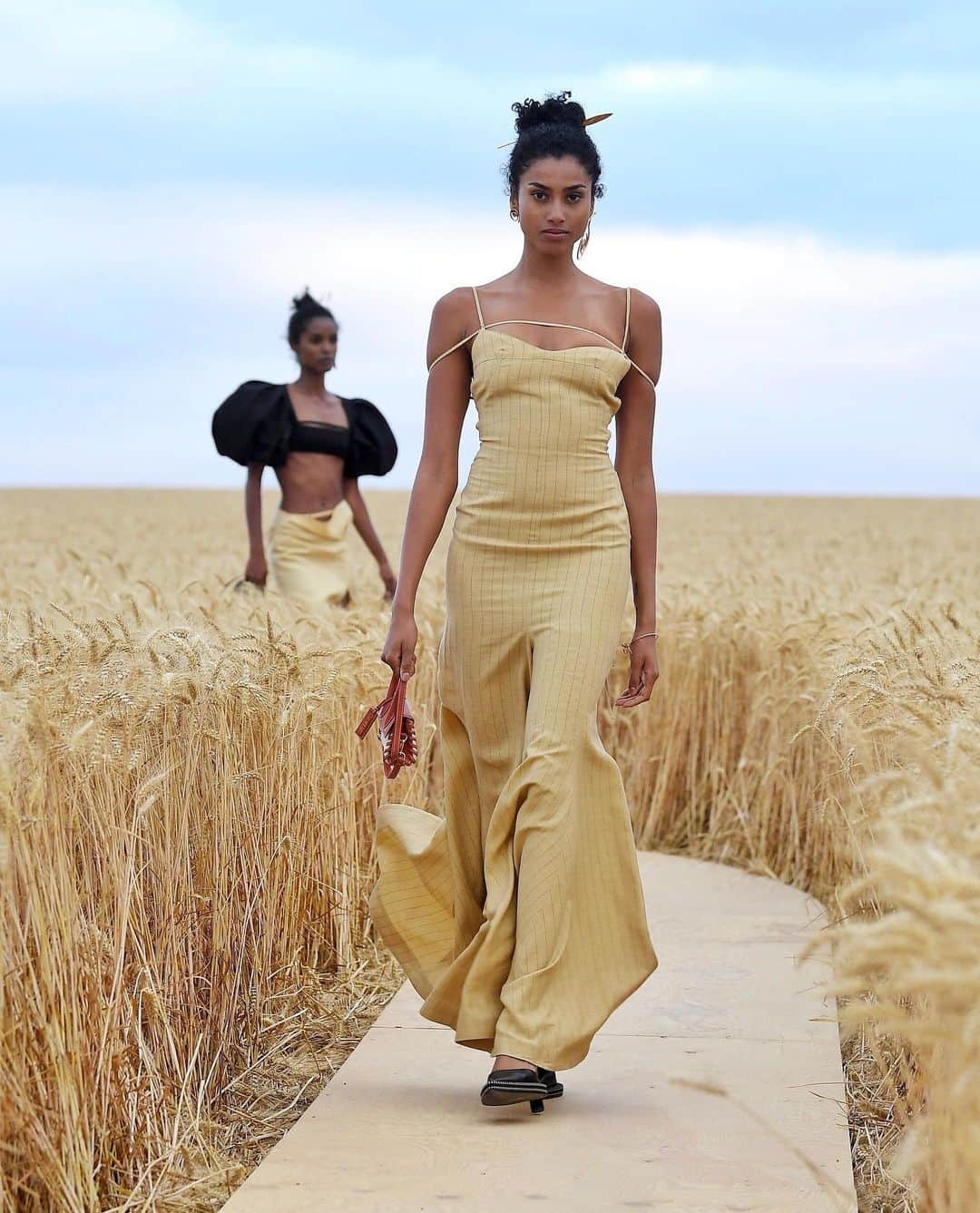 British Vogueさんのインスタグラム写真 - (British VogueInstagram)「“For me, the runway can’t be a video,” Simon Porte Jacquemus said, speaking against the dramatic backdrop of the @Jacquemus co-ed spring/summer 2021 show he staged in a rolling wheat field outside of Paris. #ImaanHammam, #AnokYai, #JillKortleve and even #Unorthodox actor #AaronAltaras starred in a dazzling line-up of models that walked the makeshift 600m wooden catwalk, winding through the crop of wheat that stretched beyond the horizon, with guests placed at socially-distanced intervals. From the designer’s declaration of love for his team, to the conversation-starter accessories, click the link in bio for the 5 things to know about the show.」7月17日 18時56分 - britishvogue