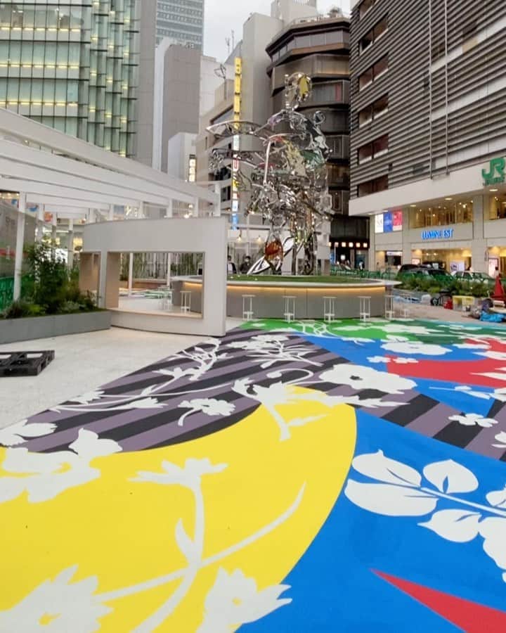 松山智一のインスタグラム：「Complete. newly born Shinjuku East Square. I m honored to have conceptualize the entire square along with my largest sculpture “Hanao-San” the new community space opens tomorrow. And yes it’s permanent.  ————  完成。多くのハードルを乗り越えて２年半かかり実現。 8m のモニュメントともに、広場のコンセプト・デザイン提案させて頂いたプロジェクト。世界最大の駅にこうした公共施設を実現することはあたらしい東京のランドマークになると考え、世界に対しての大きな文化発信に繋がると信じ構想を練ってきた。(株）ルミネ様ならびに(株）東日本旅客鉄道様の文化振興に関する寛容さと柔軟さにこの場をかりて感謝いたします。一芸術家の意見に耳を傾けて頂き、広場のもつ可能性を信じて頂いた関係者皆様に深く御礼申し上げます。 特に今回のプロジェクト進行のキーパーソン、西田香織さん @kaori.nf この場を借りて改めて深く御礼申し上げます。  明日公開。ぜひ一度お運びあれ。ここはアートを見る場所ではない、機能する場所だ！ ーーーーーー アート制作/コンセプト/全体監修:松山智一  施工:安藤ハザマ(株式会社 安藤・間) 設計:デザイン設計、デザイン監修(株)sinato 基本設計、 実施設計(株)JR 東日本建築設計  ディレクション：戸塚憲太郎 #lumineEST #shinjukuStation #HanaoSan」
