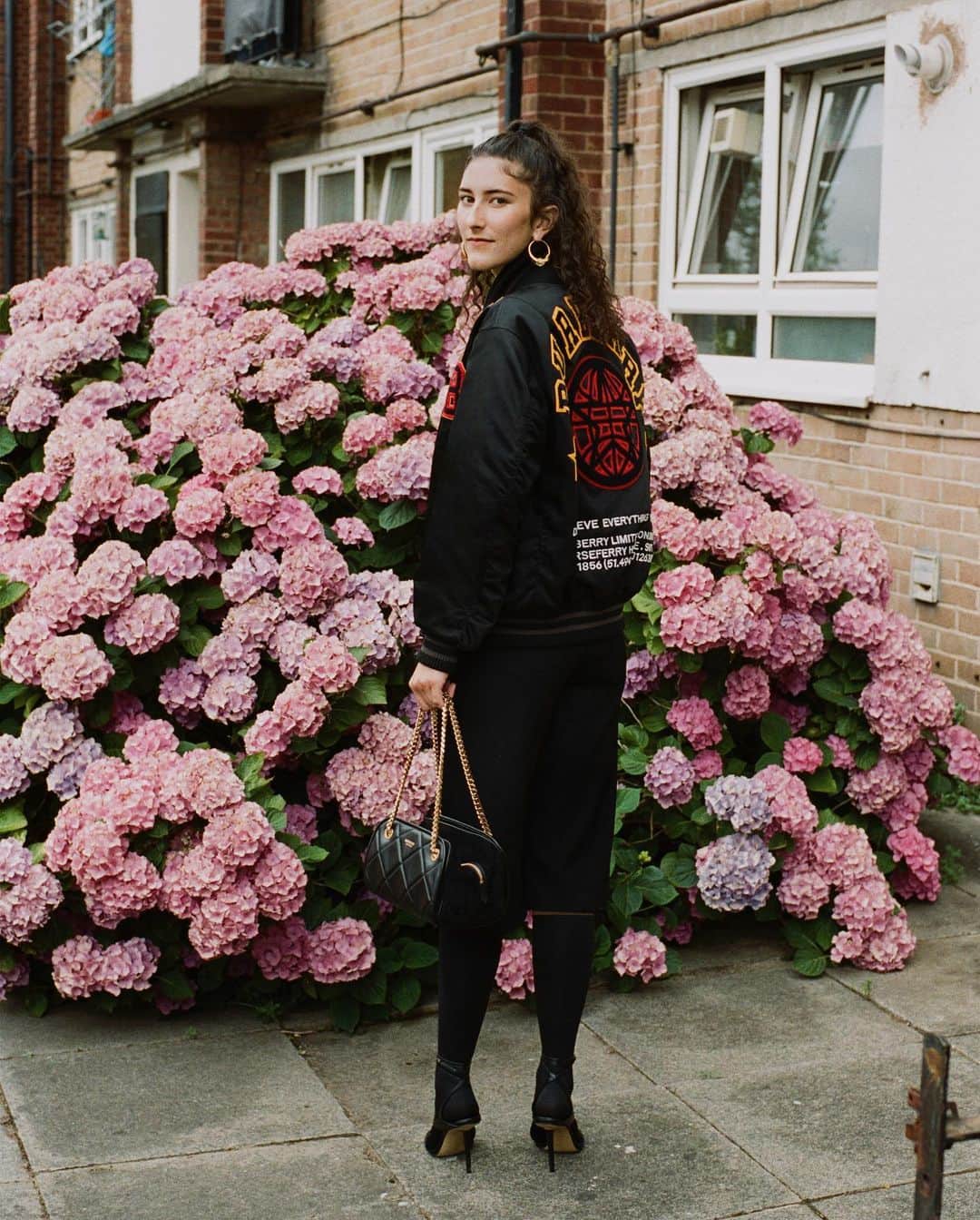 のインスタグラム：「Emily, Digital Design, Bethnal Green . Introducing our Spring/Summer 2021 pre-collection lookbook created by #RiccardoTisci – celebrating our founder Thomas Burberry’s legacy of discovery with our #Burberry community . Emily wears a showerproof technical satin bomber jacket decorated with varsity appliqués, gold-plated hoop earrings, technical wool gabardine longline shorts, a quilted leather Soft Cube bag complete with wraparound sandals . #BurberryPreSS21」