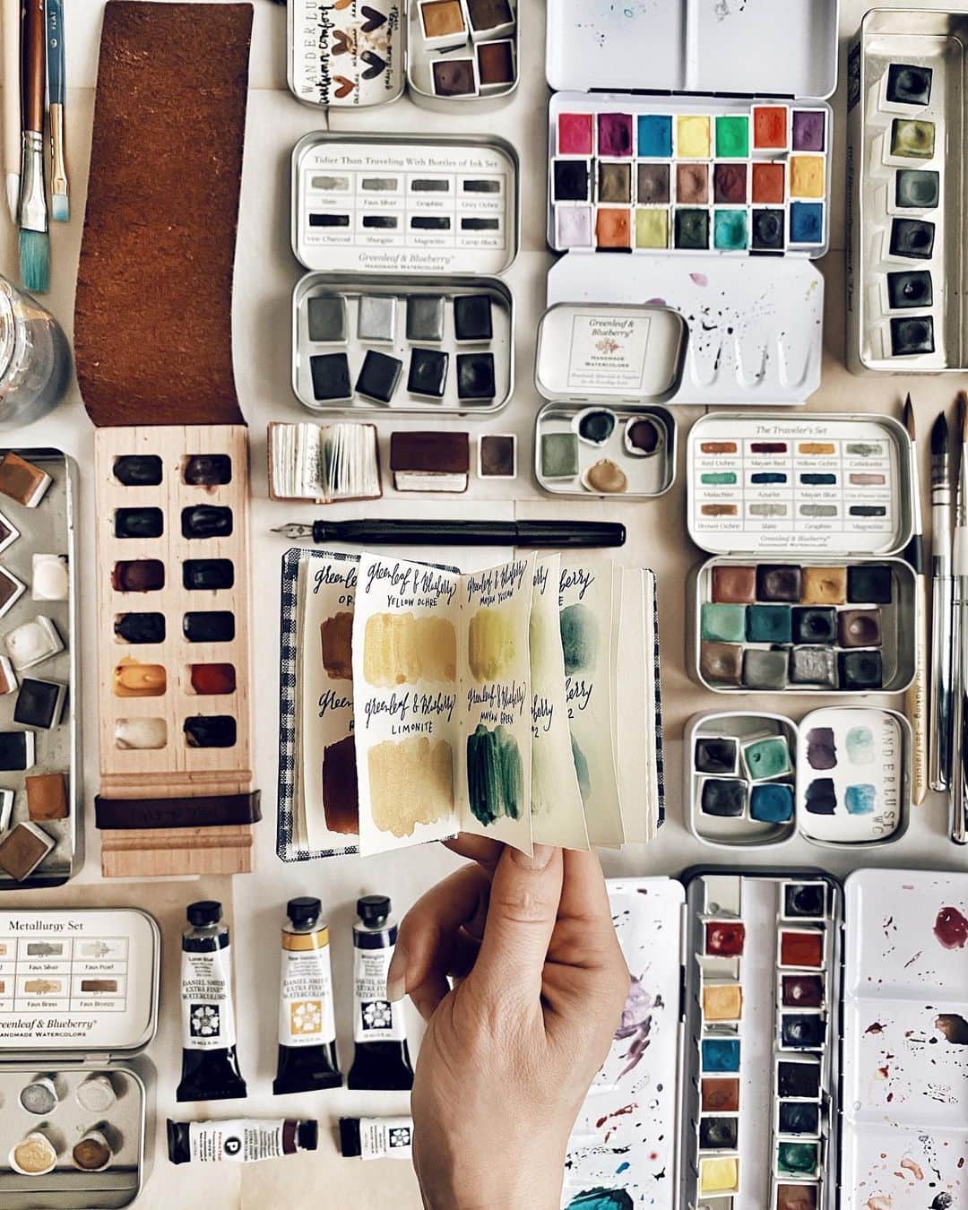 Catharine Mi-Sookさんのインスタグラム写真 - (Catharine Mi-SookInstagram)「My hobbies will forever entail an array of color, creative musings, scribblings, books, folklore and the insatiability of imaginative musings and dreams. Today I’m organizing my watercolors and as you can see I adore the personality of palettes and tins that keep these troves safely tucked. I realized that my little handmade booklet from the @pegandawl IGTV Bookbinding Tutorials did not hold enough pages halfway in swatching my paints and suddenly a 💡 went off and I realized that the @pegandawl Mini Harper Journal would make a most wonderful companion to house and categorize a growing number of watercolor swatches. I also found the perfect use for their teeny tiny Miniature Sketchbook - a swatch booklet to fit inside a tin palette. And then the final crescendo upon discovering that a palette, the Harper journal, a beloved sketch pen and paint brush with room to spare could all neatly tuck in the Scribbler Pouch. It’s the little things. I have found that this swatch journal is a most peaceful way to wind down from a hectic day helping me slow my rhythms into a needed calm. I will be spending a good portion of my weekend down time happily filling these pages. And on that, happy Friday to all! I hope the weekend brings much rejuvenation and rest. . . . Today’s palette: Mini Harper Journal, Miniature Artist Sketchbook, Iris Painter Palette & Scribbler Pouch @pegandawl. Model 65 fountain pen @franklinchristoph (a rare sighting in a beautiful Emerald on the site). Waterproof DeAtrementis Document ink @justvanness. Handmade Watercolors @greenleafblue @wanderlustwc @caseformaking. Paints in my Iris Palette @danielsmithartistsmaterials. And one of my first artist grade sets @sennelier1887. . . . . #watercolorswatches #watercolours #watercolors #pegandawl #leatherjournal #leatherjournals #handmadebook #bookbinding #handmadejournal #franklinchristoph #fountainpens #sketchpen #flatlays #flatlaylove #handmadewatercolors #greenleafblueberry #caseformaking #wanderlustwc #sennelier #danielsmithwatercolors #artsupplies #handsinframe #creativespace #artjournals #watercolorpalette #watercolorpaint #stationeryaddict」7月25日 1時34分 - catharinemisook