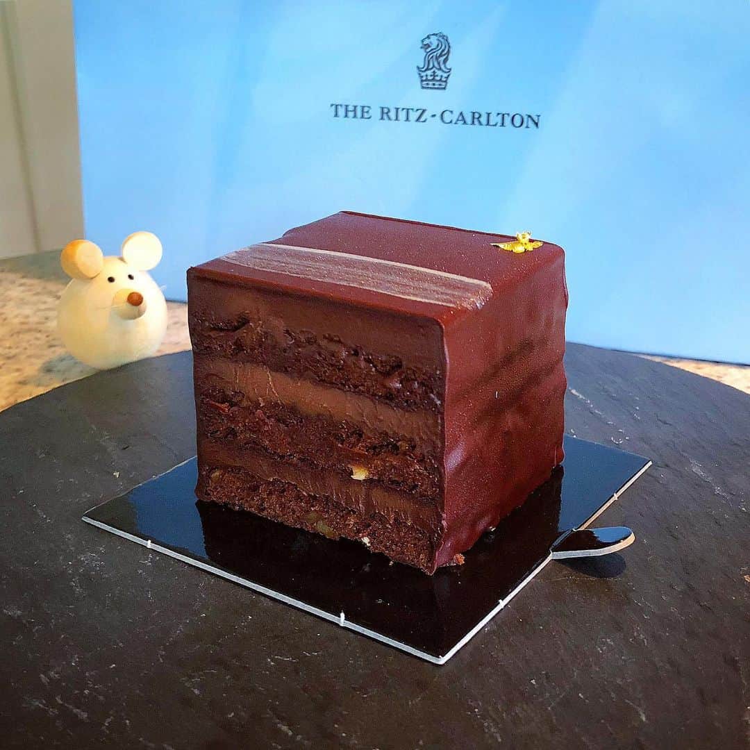 榊山敬代のインスタグラム：「🍫🍫🍫… ・ 四連休の２日目では ケーキも買いまして おうちカフェの記録  一昨日のストーリーズでは どれにしようかなシリーズ アップしていましたところ  迷いに迷いましてキュービックな チョコレートケーキセレクトの巻  チョコレートのコーティングで 守られた中にはシットリ真空な 生地が重なり時々香ばしいnuts  夜スイーツは赤ワインと食べても 大人なチョコレートケーキに変身  また後ほどストーリーズにも ケーキの模様をアップ予定也  さて今朝は食材いろいろ買い出しの巻 いつも決まった買い方をしてましたが きょうは紅茶コーナー等いつもあまり 見ないエリアも眺め楽しい買い物時間  美術館も好きだけど食品ストアを 巡るのが今は1番すきかもしれない  今日は久しぶりに〇〇〇さんを買いまして お店の方のオススメに夕食がたのしみな時 ・ ・ 🐟♪… ・ ・ ・ ・ #おうちカフェ #おうち大好き #enjoyhome ・ ・ ・ #sweets #Tokyo #チョコレート #chocolate #チョコレートケーキ #スイーツ #ご褒美 #dolce #tea #紅茶 #日本画家 の #おやつ #🍫 #リッツカールトン #東京 #RITZCarlton #theRITZCarltonTokyo #ホテルスイーツ  #テイクアウト#hotel #hotelsweets  #takeout #takeoutfood」