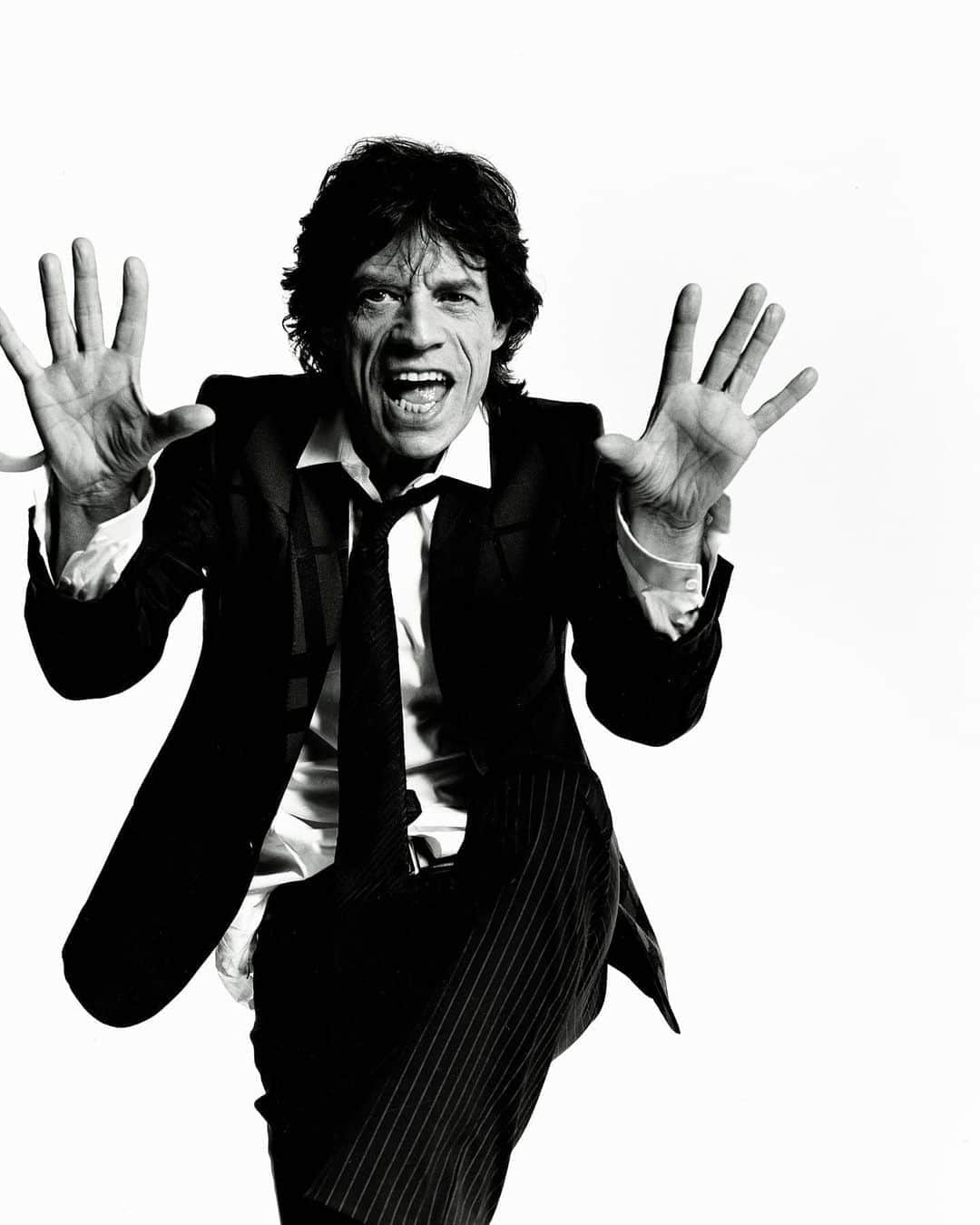マリオ・テスティーノのインスタグラム：「Today is the birthday of this icon, Mick Jagger. I went to LA from London for a day to photograph The Stones, I was given an hour at their hotel to shoot. I had shot their families before but never them together on their own, so I set up in the ballroom of their hotel with my white seamless and waited patiently. They were great, very receptive. And Mick was the funniest. After shooting him performing for the camera and following my requests he said we should swap places and shot me like this as well. Of course, I did not look as good as him, but I have a Mick Jagger portrait of myself. Happy birthday, Mick!⁣ _⁣ Hoy es el cumpleaños de este ícono, Mick Jagger. Fui a Los Angeles desde Londres por un día para fotografiar a The Rolling Stones, me dieron una hora con ellos para la sesión en el hotel. Los había fotografiado antes con sus familias antes, pero nunca solo a ellos juntos, así que me instalé en un salón de su hotel con mi fondo blanco y esperé pacientemente. Fueron increíbles, súper receptivos. Y Mick fue el más divertido. Después de fotografiarlo actuando para la cámara y siguiendo mis pedidos, dijo que deberíamos intercambiar lugares y también me fotografió así. Por supuesto, no me veía tan bien como él, pero tengo un retrato hecho por Mick Jagger. ¡Feliz cumpleaños, Mick!⁣ ⁣ MICK JAGGER, 2003⁣ ⁣ #TestinoArchive #MarioTestino #MickJagger #TheRollingStone⁣」