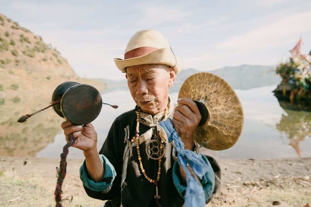 National Geographic Travelさんのインスタグラム写真 - (National Geographic TravelInstagram)「Photo by @kiliiiyuyan  Za Shi Duzhi, a shaman of the Naxi Indigenous people in southwest China, prepares for a ritual healing ceremony by spinning a pellet drum along the shoreline of Lugu Lake. Many shamanic peoples of East Asia are heavily influenced by Tibetan Buddhism. Follow me @kiliiiyuyan for more from the Indigenous world. #naxi #China #shamanism #buddhism」7月27日 5時06分 - natgeotravel
