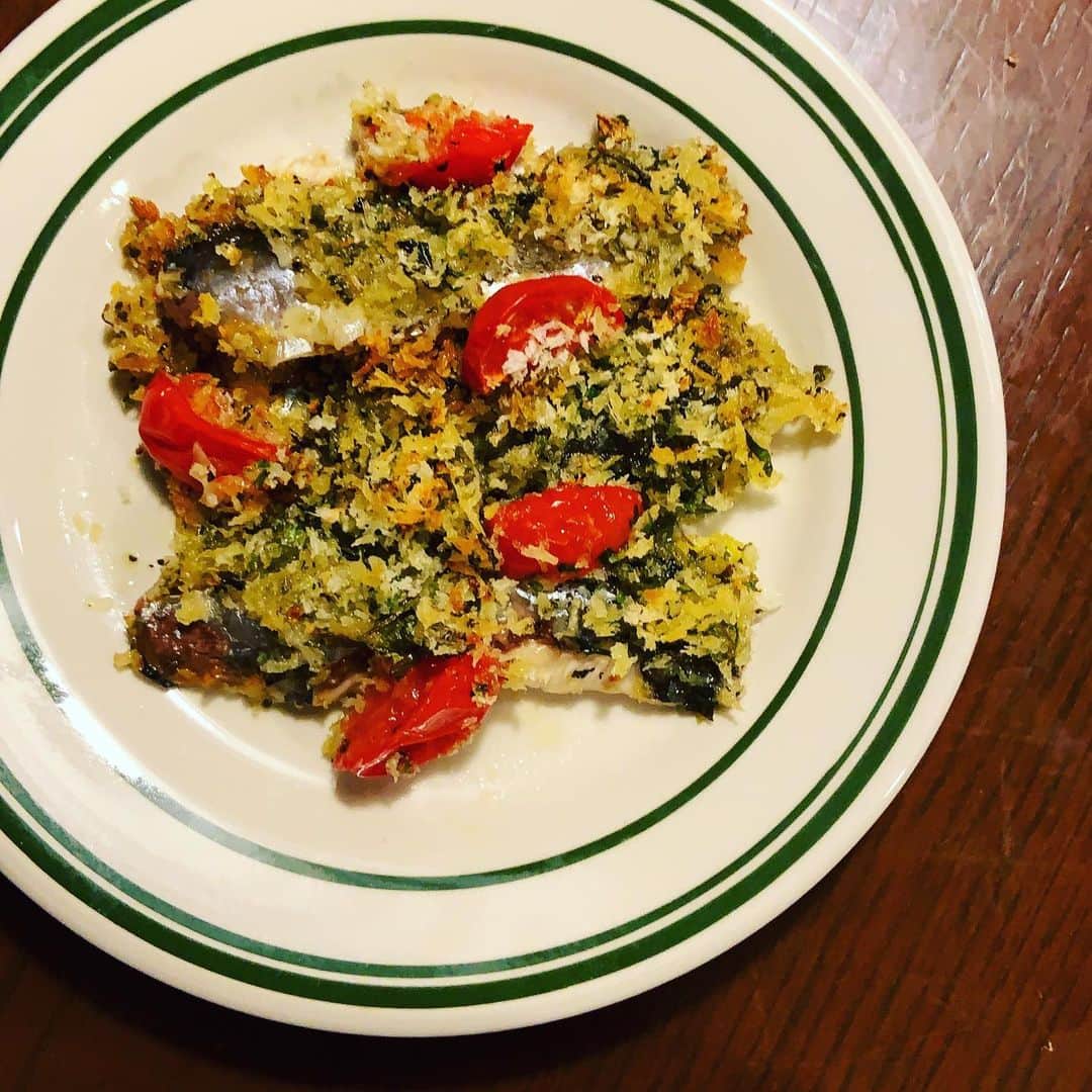 のインスタグラム：「新鮮な鰯を見つけるとついつい買ってしまう。そして香草パン粉焼きにする。 香草パン粉はイタパセ、ローズマリー、オレガノ、にんにくを刻んで混ぜるだけ。今日はフレッシュのハーブを使ったが、乾燥タイプでも。ミニトマトを散らして、パン粉をのせ、香ばしい焼き色がついたら完成。仕上げに白ワインビネガーをジュッと。 あー、美味しい。  #鰯の香草パン粉焼き」