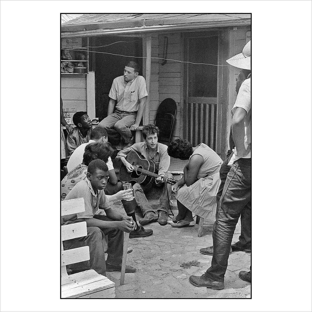 Magnum Photosさんのインスタグラム写真 - (Magnum PhotosInstagram)「"The SNCC held a Freedom Concert that day out in a field. Greenwood was a major cotton town, and the audience was field hands and household servants mostly. I was the SNCC staff photographer. The kids then in Greenwood would say, “I’m in the movement,” because Greenwood was the center of the civil rights movement in the Delta. That day, for a Freedom Concert, SNCC had brought down the Freedom Singers, Theo Bikel, Pete Seeger and Bob Dylan to perform. The big responses at the concert were for the Freedom Singers and for Theo Bikel, who sang and talked about the bond of oppression which his own background shared with the people in the field. “Blowin’ in the Wind” had been released that May and was already a huge hit, though I doubt any of the tenant farmers had ever heard it. I was fascinated by Dylan, so when I ran into him playing behind the SNCC office, I made this picture. Behind him was Mendy Samstein, a friend from the University of Chicago, Willie Blue — another close friend, a kind of hipster, from Greenwood — and listening at his knee was Bernice Reagon, future head of Swe­­et Honey in the Rock." – @dannylyonphotos⁠ .⁠ Solidarity, the July Magnum Square Print Sale, in support of the @naacp and in collaboration with @voguemagazine, is live for 1 week only!⁠ .⁠ This is a unique opportunity to purchase signed or estate-stamped prints by over 100 of the world’s leading photographic artists in an exclusive 6x6” format for $100.⁠ .⁠ Magnum photographers and Vogue are both donating 50% of their proceeds to the National Association for the Advancement of Colored People (@naacp), the longest-running, and largest civil rights organization in the United States.⁠ .⁠ The NAACP’s mission is to eliminate race-based discrimination and uphold equality of rights of all persons.⁠ .⁠ Visit the link in bio to see all the images available.⁠ .⁠ PHOTO: Bob Dylan behind the SNCC office. Greenwood, Mississippi. 1963.⁠ .⁠ © @dannylyonphotos/#MagnumPhotos⁠ ⁠ #MAGNUMSQUARE #Solidarity #printsale」7月29日 21時11分 - magnumphotos