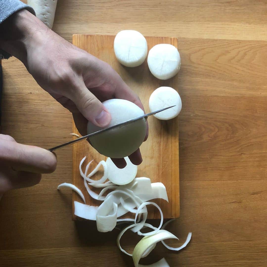 森美術館さんのインスタグラム写真 - (森美術館Instagram)「🍴 ARTISTS COOKBOOK BY MAM レシピ#12 アキラ・アキラ「大根の煮物」 現在地：シェパートン（オーストラリア）  海外生活20年を超えるアキラ・アキラ。作品に見られる細部へのこだわりは、異国で作る日本の基本料理にも。見えないところの工夫、隠し包丁は日本の美学です。そして、森美術館のシリーズ展「六本木クロッシング」が、ニュージーランド、ニュー・プリマスでの繋がりを生んでいるのも嬉しいストーリー。  • 料理にまつわるストーリー ニュージーランド北島のニュー・プリマスに住んでいた頃、キュレーターである私のパートナーが、プロジェクトで一緒になったアーティストたちをもてなすのによく料理をしていました。ニュー・プリマスは少し辺鄙な場所にあり、アーティストは皆、遠方からはるばる時間をかけて来てくれるので、滞在初日の夜には自宅に招き、私が彼らのために栄養たっぷりの料理を作ってあげるのが習慣になりました。この「典型的な」日本食を、毛利悠子さん（「六本木クロッシング2016展」参加）や、田村友一郎さん（「六本木クロッシング2019展」参加）などアーティストのために料理するのは、私の楽しみでした。この一皿は田村さんを唸らせ、私が食堂を開けるとまで言ってくれたのです！  • 所要時間 2時間強⏱  • 材料 大根 米のとぎ汁（または、水＋小さじ1杯程度の生米） 出汁 150 ml　（作り方は以下を参照） 粗糖 大さじ1杯 みりん 大さじ1杯 薄口醤油 大さじ2杯 和からし  • レシピ 出汁を作るには、まず、小鍋に700 mlの水に対して7 グラム程度の昆布を入れ30分ほど放置したあと、弱火にかける。沸騰する直前で火を止め、鰹節をひとつかみ足したら、再度中火にかけ、沸騰させたら火を弱め4分ほどコトコト煮立てたら、火を止める。冷ましたら濾し、出来上がり。お味噌汁にも使えます。  ＜大根の煮かた＞ 1. 生の大根を3センチ程度の厚さに輪切りし、周りの皮をむく。 2. それぞれの角を綺麗に面取りする。  3. それぞれ両面とも、中心に深さ5ミリ程度の切れ目を十字に入れる（隠し包丁）。  4. 小鍋に輪切りにした大根を入れ、少し温めた米のとぎ汁で大根を覆う（これが大根を柔らかく煮るコツ）。とぎ汁がない場合は、小さじ1杯程度の生米と水で代用する。  5. 1時間半ほど煮たら、大根から水気を切り、鍋は洗う。  6. 大根を洗った鍋に戻し、今度は水を大根がかくれるくらい入れる。20分ほど煮立てたら、再度水を切る。  7. 出汁を加えたら火にかけ、とろ火で煮る。  8. 砂糖を加えて溶けたら、みりん、そして薄口醤油を加える。味見をして調整。  9. とろ火で再度、大根の色が一緒に煮ている水分と同じ色になるまで静かに煮たら、出来上がり。和からしを添えてテーブルに。🙂  #ArtistsCookbookByMAM #AkiraAkira #MoriArtMuseum #MuseumFromHome #Cookbook」7月29日 23時30分 - moriartmuseum