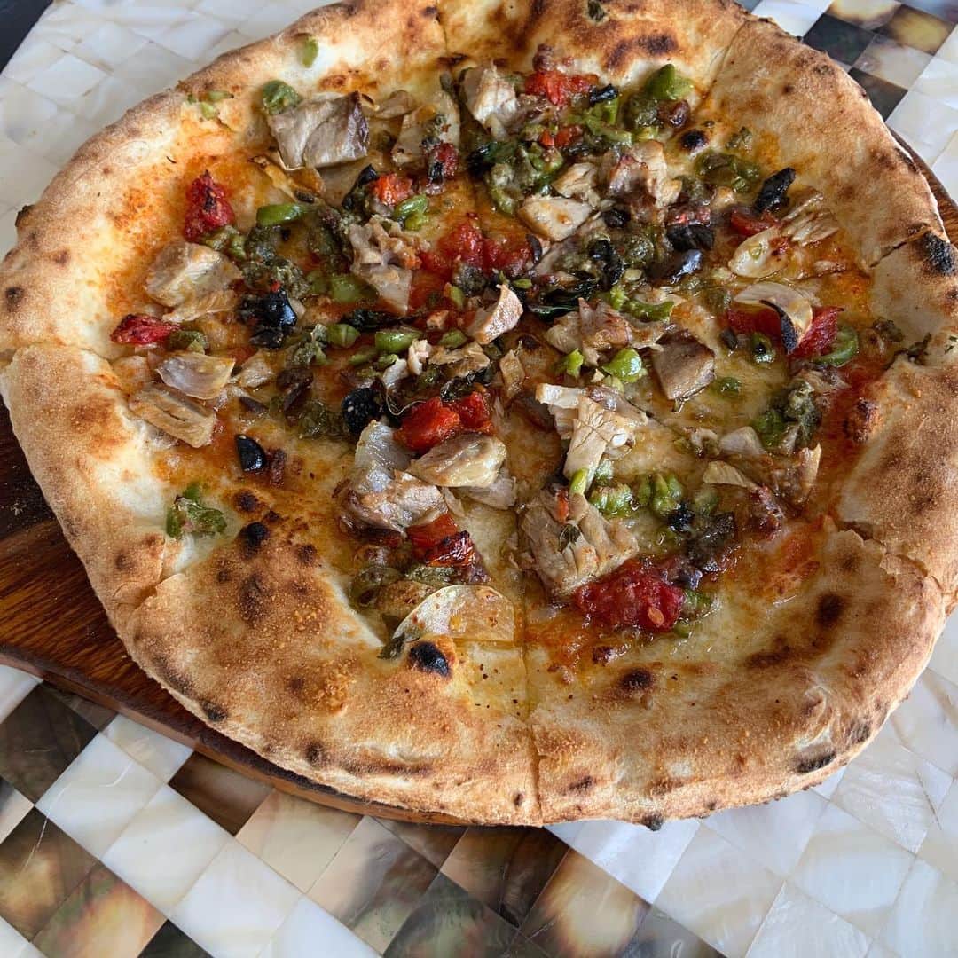 ポジリポさんのインスタグラム写真 - (ポジリポInstagram)「〜Weekly Pasta〜  【グリルスルメイカとドライトマトの大葉ジェノベーゼ】  旬のスルメイカと大葉を使ったパスタ。 スルメイカは炭で焼いて味と香りをたたせ、大葉と相性のいい大根の葉はあまり火を入れず食感と少し苦味を残し加えてます。 ドライトマトの酸味と仕上げにローストしたカシューナッツをアクセントに加えた大葉の爽やかな香りのするパスタになってます。  〜Weekly Pizza〜   Pizza alla Eoliana 『エオリア風ピッツァ』   シチリア島 北方に Isole Eolie と呼ばれる7つの火山性諸島があります。  有名なのはヴルカーノ島 ストロンボリ島 リーパリ島 サリーナ島、、、、 このサリーナ島のケッパーが特に名産で、火山の火口だった所に植えたらとんでもなく美味しい抜群の味になったことからエオリア風という料理が始まったと言われます。  このエオリア風のソースは各諸島 各集落 様々なバリエーションがありますが、 基本的に入るのはケッパー、バジリコ、トマト バジリコ、ブラックオリーブ、唐辛子、ニンニクです。   ここにマグロの尾肉をプラス。  腹側のトロっとした脂質 筋のプルっとした食感、背側のまるで肉のような食感、そして骨もあるから、髄液の旨味、コラーゲンも楽しめる。ケッパーやアンチョビと組み合わさるとマグロは更に化けます。 #地域共通クーポン沖縄」7月30日 7時52分 - posillipo_okinawa