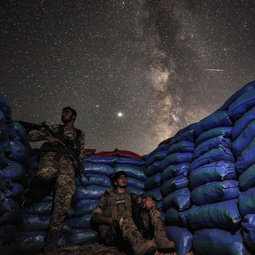 のインスタグラム：「AFP Photo 📷 @omar_hajkadour - This long-exposure picture taken early on July 23, 2020, shows the Milky Way galaxy rising in the sky above Syrian fighters of the Turkish-backed National Front for Liberation group while on watch duty between sandbags in the town of Taftanaz along the frontlines in the country's rebel-held northwestern Idlib province.」