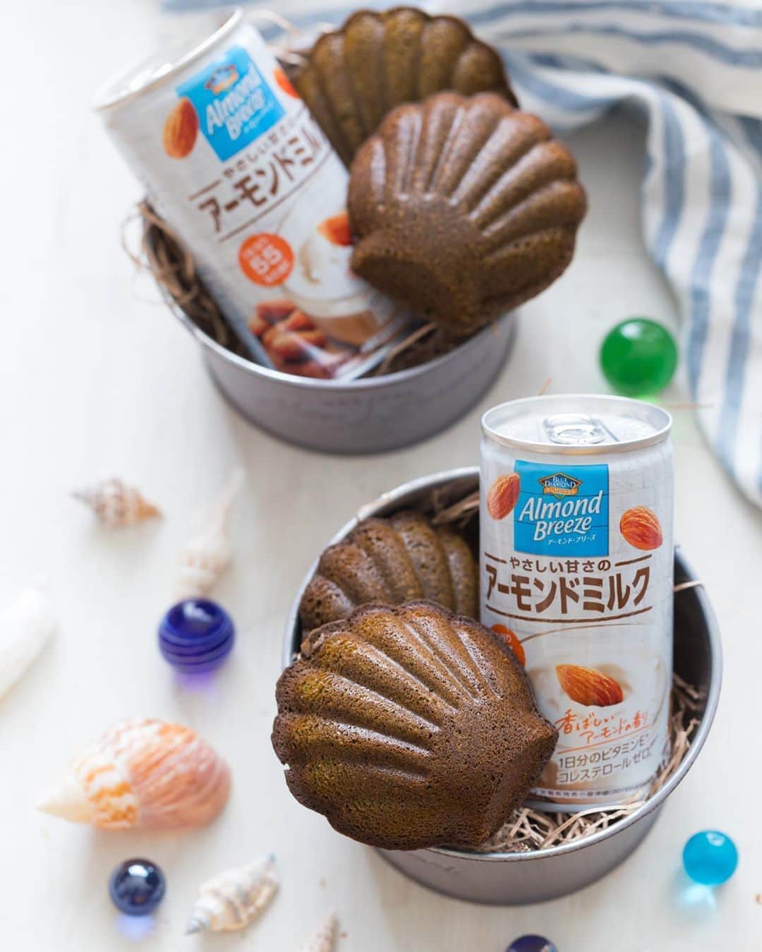 のインスタグラム：「夏は冷たいアーモンドミルクがオススメ🥛🧊 . 「やさしい甘さのアーモンドミルク」はさらさらとした口当たりで、おやつの時間に焼き菓子と合わせたり、ちょっと甘いドリンクが飲みたい時なんかにもぴったりです🥧 . 日本限定の商品で、和菓子との相性も良いので、ぜひお試しください🍡 . . #ブルーダイヤモンドアーモンド #アーモンドブリーズ #アーモンドミルク #productofcalifornia #madewithcaliforniaalmonds #bluediamondgrowers #almondbreeze #bluediamondalmonds #アーモンド #植物性ミルク #お菓子部 # #お菓子のある毎日 #お菓子好き #焼き菓子 #フランス菓子 #おやつタイム #マドレーヌ #madeleine #貝殻 #シェル #パティシエカメラ部 #ビー玉 #夏雑貨 #和ガラス #キラキラ」
