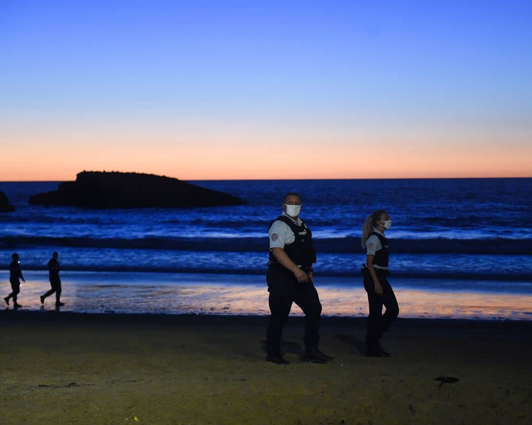 ルモンドさんのインスタグラム写真 - (ルモンドInstagram)「Il est 21 h 30 lorsqu’une voix retentit dans le haut-parleur : « Pour des raisons sanitaires, les accès aux plages de Biarritz sont désormais interdits de 22 heures à 6 heures. » Les quelques centaines de personnes assises par petites grappes sur le sable de la grande plage, située au cœur de la station balnéaire basque, tendent l’oreille mais ne bougent pas.⁣ Nous sommes le mardi 4 août, une douzaine de policiers nationaux et municipaux sont postés devant l’escalier principal, au pied du Casino, prêts à faire respecter le nouvel arrêté municipal. Un quart d’heure plus tard, le message est de nouveau diffusé. A 21 h 55, les vacanciers remballent d’eux-mêmes rosé, chips et serviettes, tandis que les derniers surfeurs sortent de l’eau. Les forces de l’ordre ferment les barrières. Dans le calme. A 22 h 05, la plage est déserte.⁣ Le Sud-Ouest est l’une des régions « les moins impactées » depuis le début de la crise sanitaire liée au Covid-19, selon l’agence régionale de santé (ARS) de Nouvelle-Aquitaine. Et il compte bien le rester. Alors que les aoûtiens déferlent sur la côte basco-landaise, élus, collectivités, commerçants, services de l’Etat et forces de l’ordre redoublent de vigilance. Port du masque obligatoire dans certaines rues, traque aux fêtes clandestines, fermeture des plages la nuit, gel hydroalcoolique dans les magasins, campagnes de tests de dépistage (38 000 cette semaine, 30 000 la semaine précédente, selon la préfecture de Nouvelle-Aquitaine)… A Bayonne, Biarritz, Anglet, Mimizan ou encore Hossegor, les mesures de précaution se multiplient pour éviter « à tout prix » une propagation du virus, jusque-là très contenu.⁣ -⁣ 1 : Des policiers patrouillent sur la «Grand Plage» de Biarritz, dans le sud de la France, le 4 août.⁣ 2 : La plage de Biarritz est fermée toute la nuit à partir de 22 heures jusqu'à 6 heures du matin, le 5 août.⁣ Photos : Gaizka Iroz / AFP - Bob Edme / Ap photo⁣ -⁣ #france #plage #covid #biarritz #police」8月8日 2時24分 - lemondefr