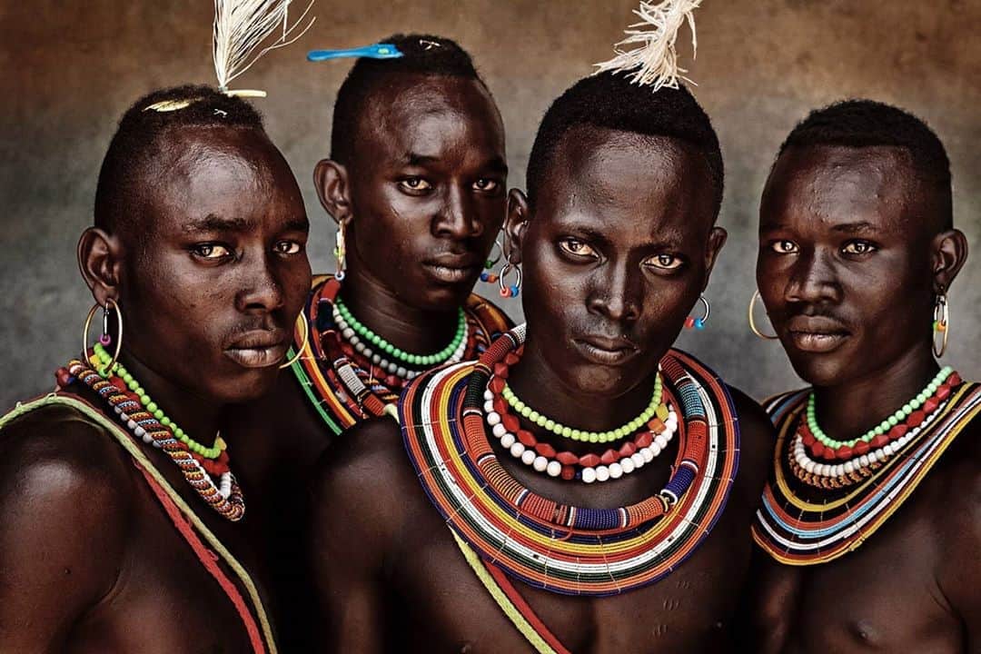 マリオ・テスティーノのインスタグラム：「I was so inspired when meeting these men from the Pokot community. We had to take a helicopter to get to them and as we were landing a big part of the community had gathered for us to do some portraits. Their looks and beauty were serious. I love how they mix their traditions with modern accessories they find, like the comb here. The way they use their beading and necklaces to identify themselves is magical. These men were the quiet ones. I photographed so many that had bigger accessories, but my eyes went to this group to start with, I saw they had a lot of strength. ⁣⁣ Kenya is an amazing country to come across traditions from communities close to each other but very different. I am longing to go back to carry on meeting their amazing people.⁣⁣ _⁣⁣ Conocer a este grupo de la comunidad Pokot fue tan inspirador. Tuvimos que tomar un helicóptero para llegar hasta ellos y mientras aterrizamos una gran parte de la comunidad se había reunido para que les hiciéramos retratos. Su apariencia y belleza eran increíbles. Me encanta cómo mezclan sus tradiciones con accesorios modernos que encuentran, como el peine que se ve en esta fotografía. La forma en la que usan sus cuentas y collares para identificarse es mágica. Estos hombres eran los más sutiles. Fotografié a tantos que tenían accesorios más grandes, pero mis ojos se dirigieron a este grupo para empezar, me di cuenta de que tenían una fuerza especial.  Kenia es un país asombroso donde comunidades cercanas pueden tener tradiciones muy diferentes. Estoy deseando volver para seguir conociendo a su increíble gente.⁣⁣ _⁣⁣ ⁣⁣ WORLD INDIGENOUS PEOPLE’S DAY. ⁣⁣ DÍA INTERNACIONAL DE LOS PUEBLOS INDÍGENAS. ⁣⁣ ⁣⁣ #IndigenousPeoplesDay #ABeautifulWorld #MarioTestino⁣」