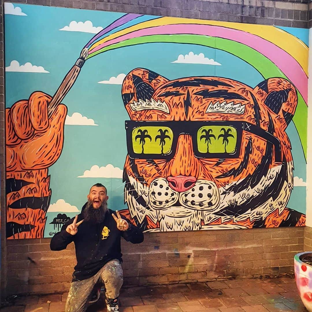 MULGAさんのインスタグラム写真 - (MULGAInstagram)「It's Tiny the Tiger 🐯, a mural I had the pleasure of painting at Shore Preparatory School. I painted Tiny with a couple of students after doing some talks and workshops.⁣ ⁣ Cheers to everyone who suggested names for this tiger and cheers to Kate and the crew at school for having me in to throw some paint and cheers to @tint.paint for providing said paint. ⁣ ⁣ The story of Tiny the Tiger 🐯  ⁣ Once there was a tiger called Tiny the Tiger and when he was born he was the littlest one in his fam and his big bros and sisters and cousins would always rough him up and he couldn't do much about it cause he was a tiny little thing. When he reached adolescence he went through a growth spurt and grew into the biggest tiger that the whole of Tigertown had ever seen. He enjoyed roughing up his siblings and cousins after that cause he always had the upper hand. One day when he was climbing a tree he was too heavy and it snapped in half and in the middle of the trunk he discovered a big magical paintbrush. He started painting with it and  everything he painted turned into real things. Like one time he painted the rainbow and it became a real rainbow and it even had a magical pot of gold at the end of it. He also painted a lot of Snickers bars because he loved a good Snickers.⁣ ⁣ The End⁣ ⁣ #mulgatheartist #tiger #muralart #schoolmural #tigerart #snickers #tintpaint」8月10日 10時23分 - mulgatheartist