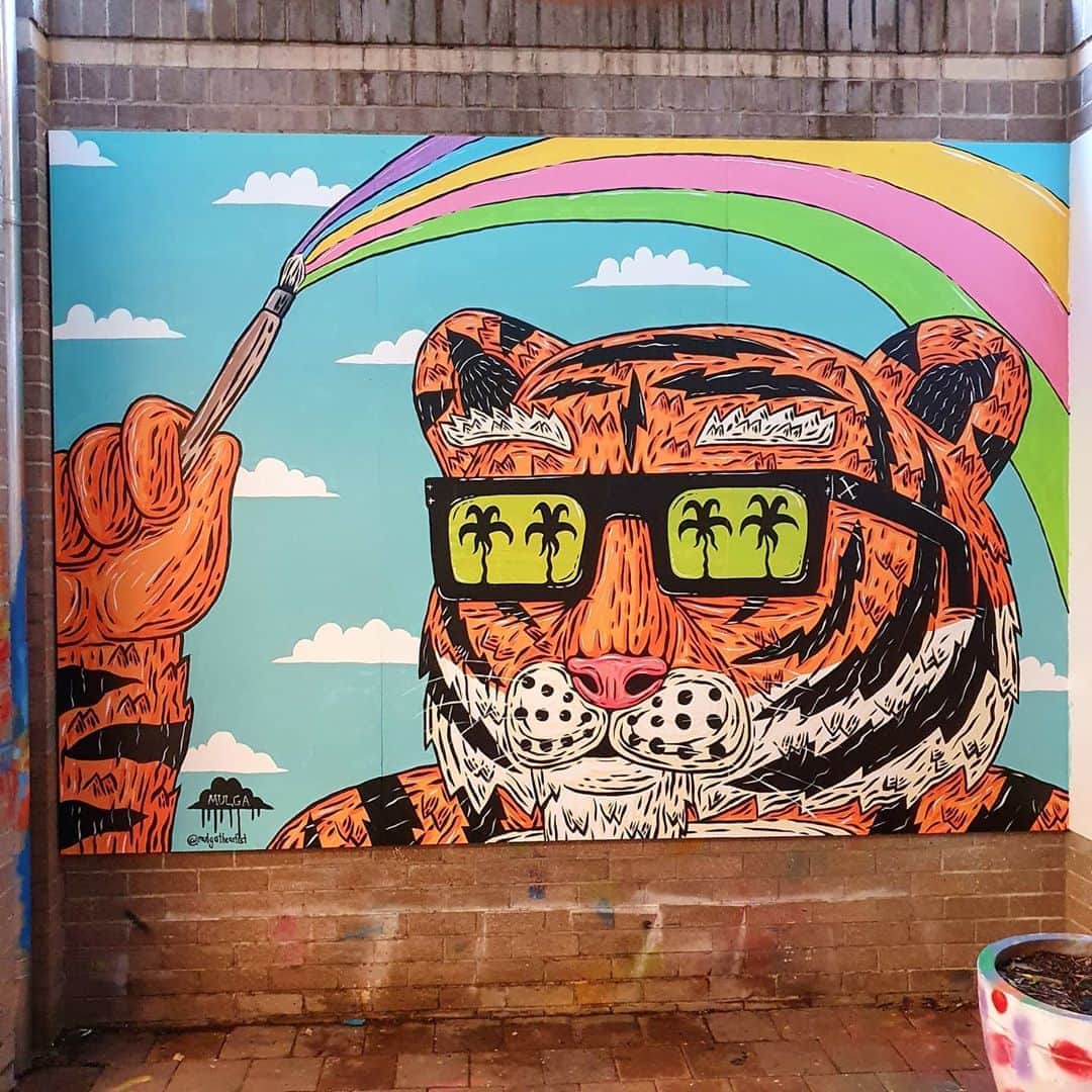 MULGAさんのインスタグラム写真 - (MULGAInstagram)「It's Tiny the Tiger 🐯, a mural I had the pleasure of painting at Shore Preparatory School. I painted Tiny with a couple of students after doing some talks and workshops.⁣ ⁣ Cheers to everyone who suggested names for this tiger and cheers to Kate and the crew at school for having me in to throw some paint and cheers to @tint.paint for providing said paint. ⁣ ⁣ The story of Tiny the Tiger 🐯  ⁣ Once there was a tiger called Tiny the Tiger and when he was born he was the littlest one in his fam and his big bros and sisters and cousins would always rough him up and he couldn't do much about it cause he was a tiny little thing. When he reached adolescence he went through a growth spurt and grew into the biggest tiger that the whole of Tigertown had ever seen. He enjoyed roughing up his siblings and cousins after that cause he always had the upper hand. One day when he was climbing a tree he was too heavy and it snapped in half and in the middle of the trunk he discovered a big magical paintbrush. He started painting with it and  everything he painted turned into real things. Like one time he painted the rainbow and it became a real rainbow and it even had a magical pot of gold at the end of it. He also painted a lot of Snickers bars because he loved a good Snickers.⁣ ⁣ The End⁣ ⁣ #mulgatheartist #tiger #muralart #schoolmural #tigerart #snickers #tintpaint」8月10日 10時23分 - mulgatheartist