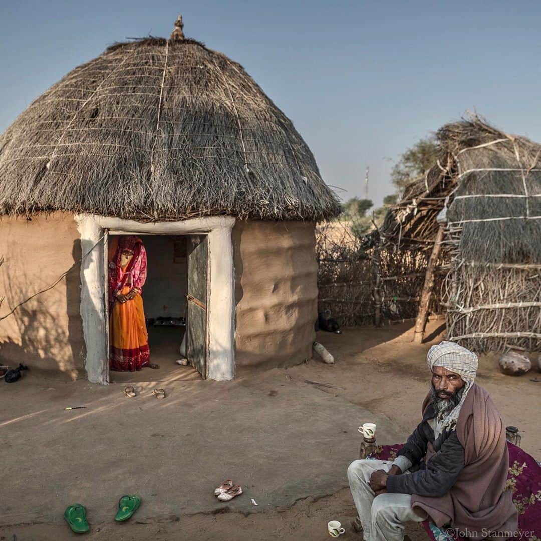 のインスタグラム：「On a borrowed piece of arid land, Aarti had entered one of several small structures finding tea leaves to boil more chai. Her husband walked over, but only his shadow barely entered, and a family member wrapped in a blanket on that chilly early day in December had awoken on a cot next to shoes whose wearer I never knew. That day was like so many, completely random, always in the accompaniment of generous, kind people as Aarti and her family of farm laborers in Churu, Rajasthan. I will never forget the poignant sweet taste of Aarti’s chai with ground cloves I sipped from the white cup balancing on the cot’s bedpost. A thankful hot spicy dose I needed that morning in India when I was carrying overthinking heaviness. ⠀⠀⠀⠀⠀⠀⠀ India’s Daunting Challenge: There’s Water Everywhere, And Nowhere - Chapter 8 of the @outofedenwalk, my latest story last months (August 2020) issue of @natgeo magazine. ⠀⠀⠀⠀⠀⠀⠀ #shadow #greenflipflop #shoes #cot #bed #churi #rajasthan #india @natgeo @outofedenwalk #walkingindia #edenwalk」