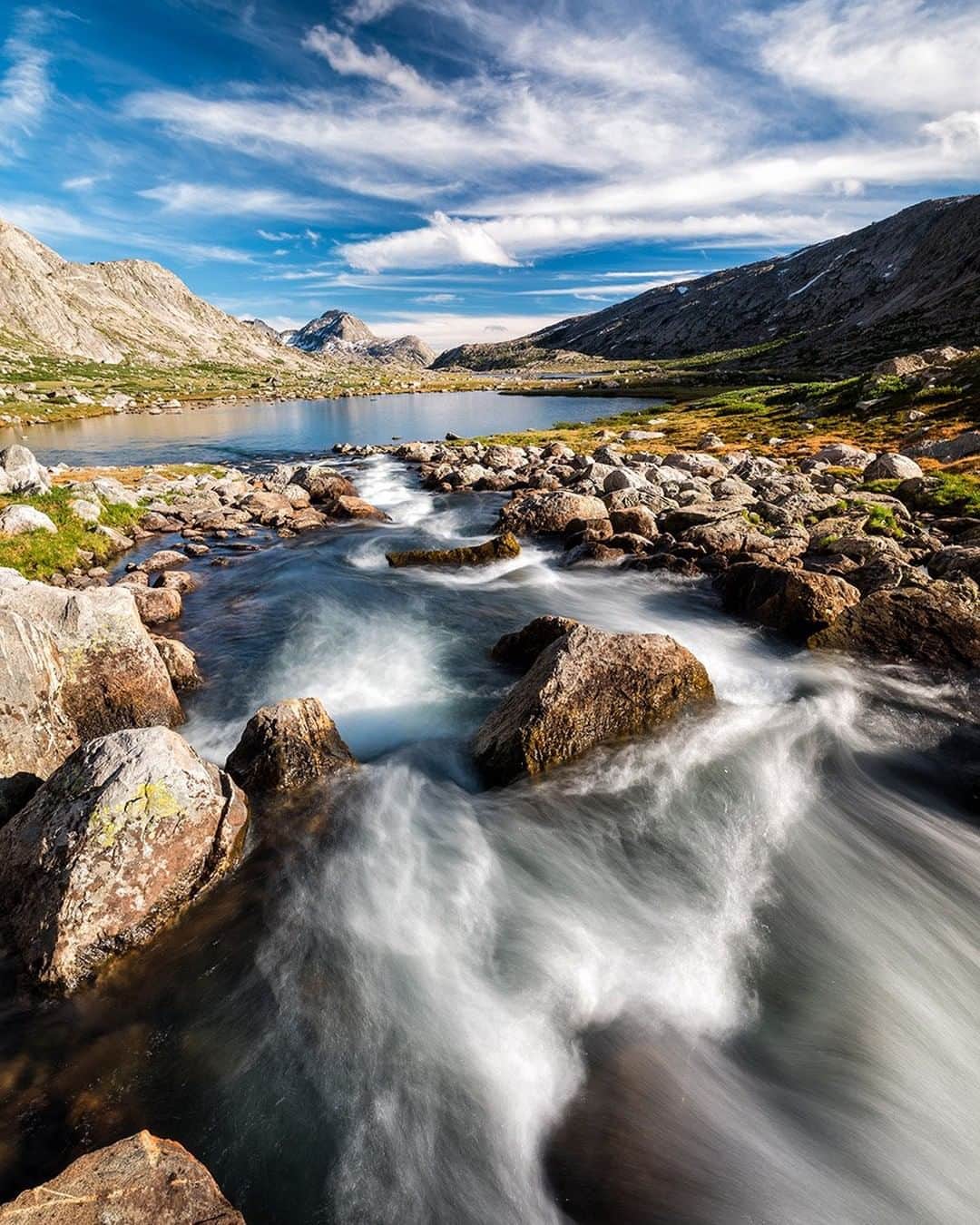 National Geographic Travelさんのインスタグラム写真 - (National Geographic TravelInstagram)「Photo by @stephen_matera  A creek cascades over rocks toward an alpine lake in the Wind River Range. The mountains, or the Winds as they are known, are a subrange of the Rocky Mountains. They are less known than their Teton siblings, but they are a bigger range that also contains the highest peak in Wyoming, Gannett Peak (not shown here), at over 13,800 feet (4,206 meters). The Winds have more than 150 alpine glaciers and over a thousand lakes.  Follow me @stephen_matera for more images like this from Wyoming and around the world. #windriverrange #wyoming #wilderness」8月18日 13時10分 - natgeotravel